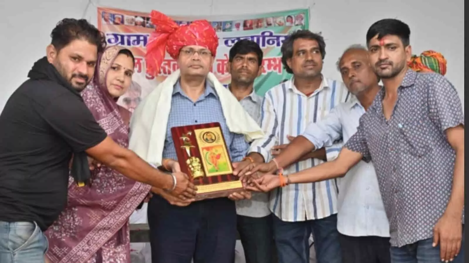 तस्वीर में बाएं से दाएं खड़े लोग कार्यक्रम के दौरान एक व्यक्ति को सम्मानस्वरूप प्रतीक चिन्ह भेंट कर रहे हैं। तस्वीर में बाएं से दाएं खड़े लोग कार्यक्रम के दौरान एक व्यक्ति को सम्मानस्वरूप प्रतीक चिन्ह भेंट कर रहे हैं।