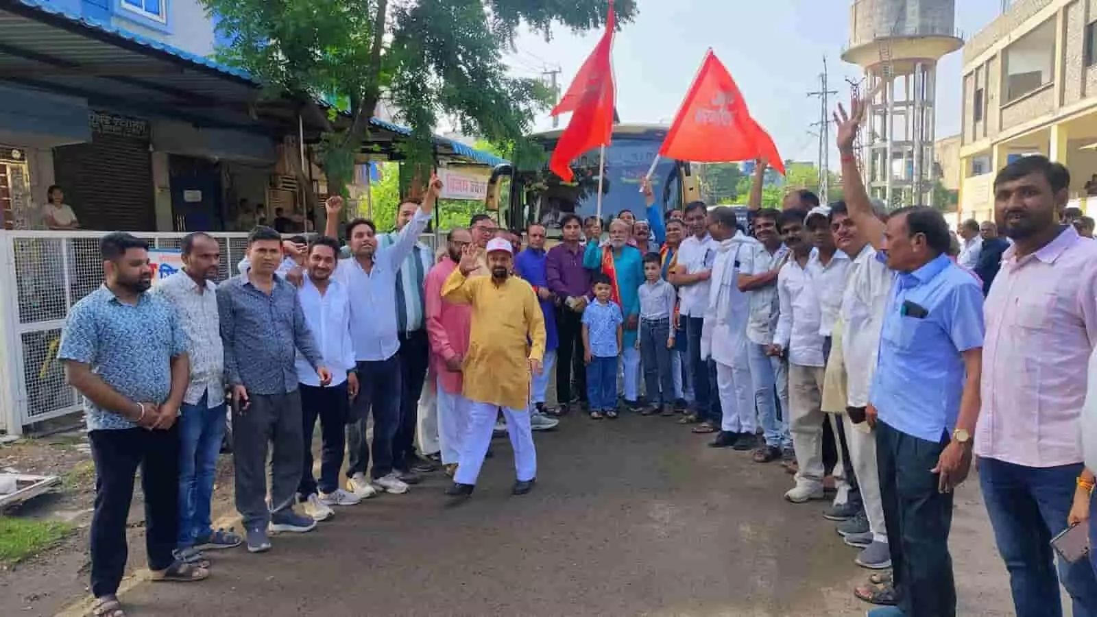 तस्वीर में बाएं से दाएं खड़े कई लोग और बच्चे सड़क पर बसों के पास हाथ उठाकर खड़े दिखाई दे रहे हैं. तस्वीर में बाएं से दाएं खड़े कई लोग और बच्चे सड़क पर बसों के पास हाथ उठाकर खड़े दिखाई दे रहे हैं.