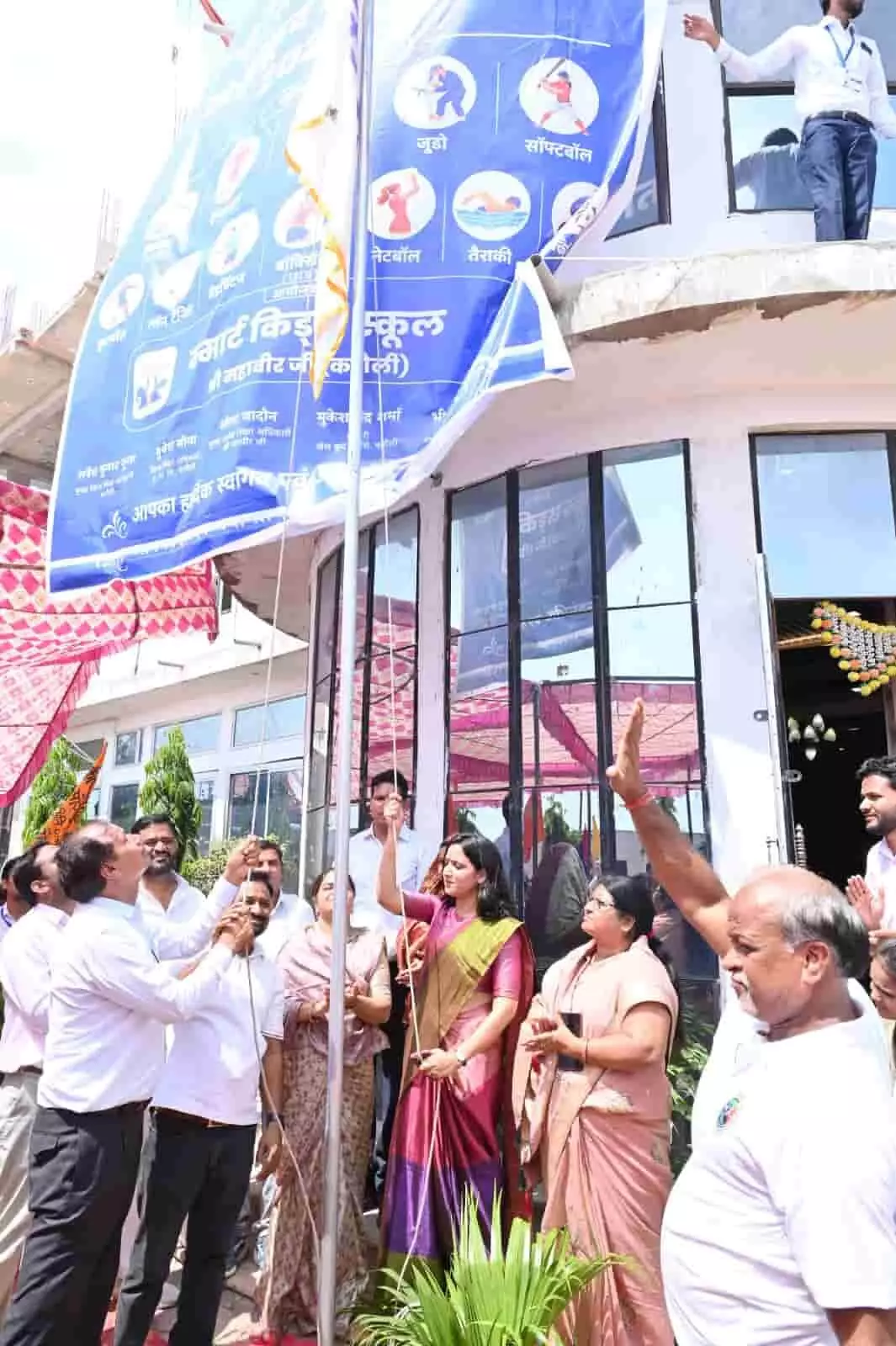 तस्वीर में बाएं से खड़े लोग, केंद्र में झंडा खींचती हुई महिला अतिथि और दाएं तरफ खड़े अन्य अतिथि दिखाई दे रहे हैं। तस्वीर में बाएं से खड़े लोग, केंद्र में झंडा खींचती हुई महिला अतिथि और दाएं तरफ खड़े अन्य अतिथि दिखाई दे रहे हैं।