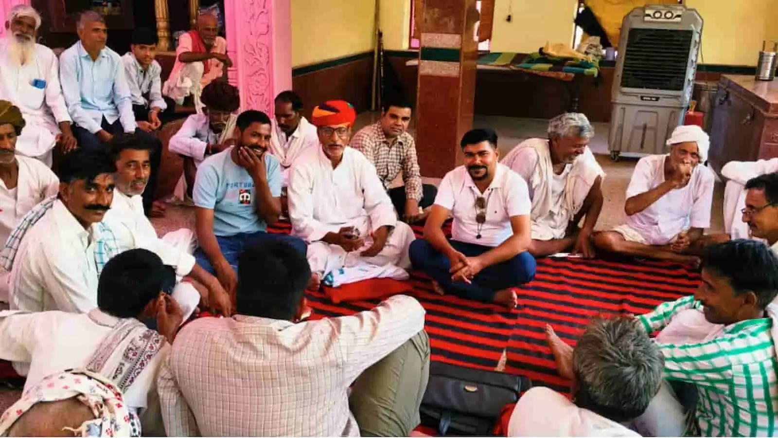 तस्वीर में जमीन पर दरी पर बैठे हुए कई ग्रामीण, बुजुर्ग और समिति के सदस्य दिखाई दे रहे हैं। तस्वीर में जमीन पर दरी पर बैठे हुए कई ग्रामीण, बुजुर्ग और समिति के सदस्य दिखाई दे रहे हैं।