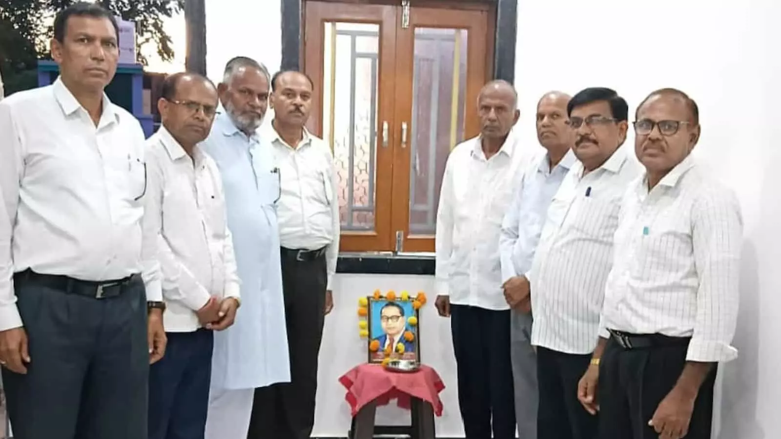 तस्वीर में बाएं से दाएं सफेद शर्ट और पैंट पहने हुए कई पुरुष एक कमरे में खड़े हुए दिखाई दे रहे हैं। तस्वीर में बाएं से दाएं सफेद शर्ट और पैंट पहने हुए कई पुरुष एक कमरे में खड़े हुए दिखाई दे रहे हैं।