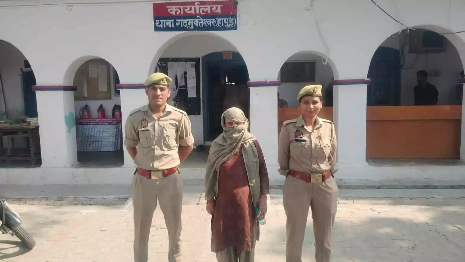तस्वीर में गढ़मुक्तेश्वर थाने के सामने बाएं एक पुलिसकर्मी, बीच में महिला और दाएं एक महिला कांस्टेबल दिख रही हैं। तस्वीर में गढ़मुक्तेश्वर थाने के सामने बाएं एक पुलिसकर्मी, बीच में महिला और दाएं एक महिला कांस्टेबल दिख रही हैं।