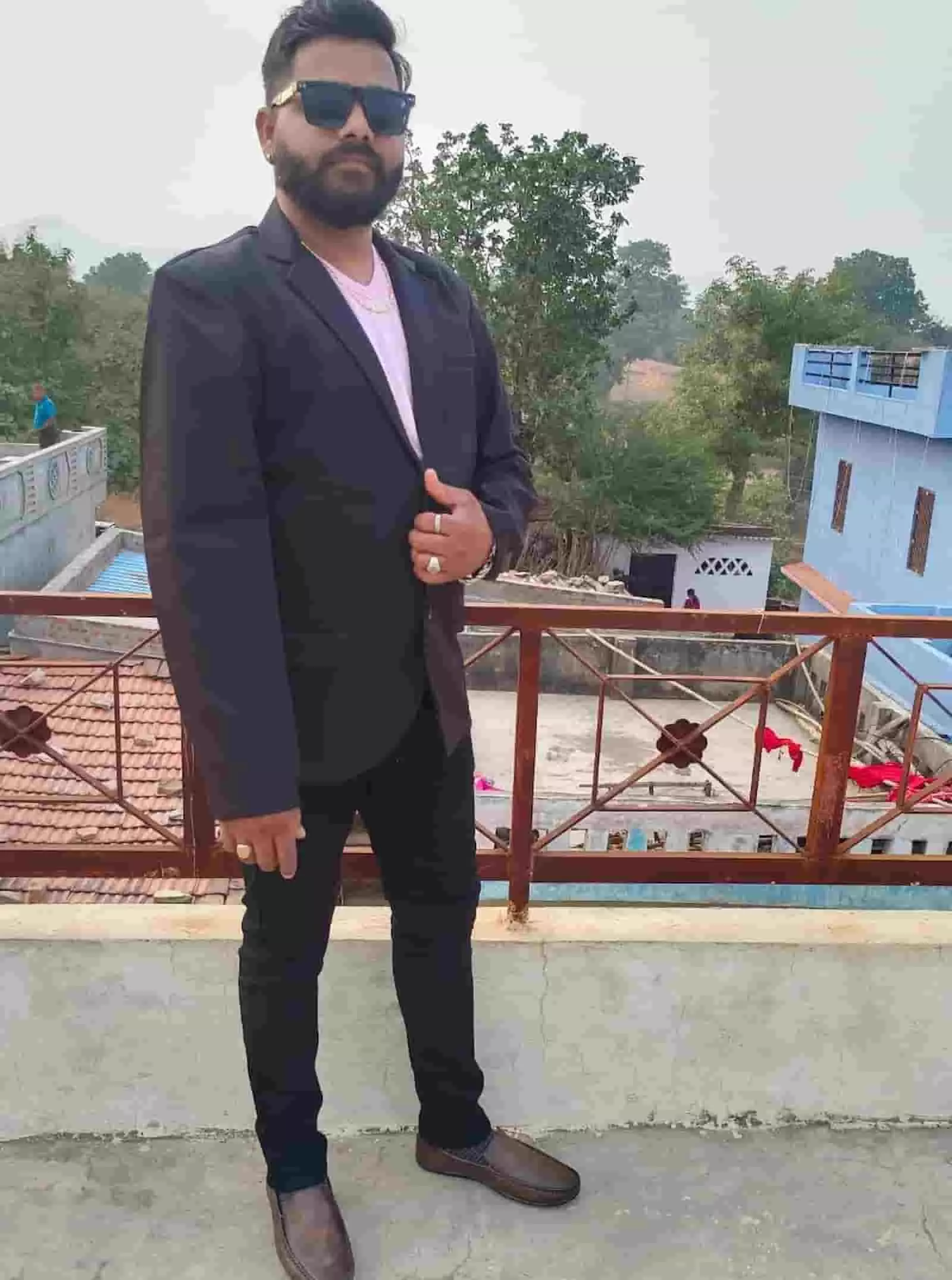 छत पर रेलिंग के पास चश्मा और कोट पहने खड़ा एक व्यक्ति। छत पर रेलिंग के पास चश्मा और कोट पहने खड़ा एक व्यक्ति।