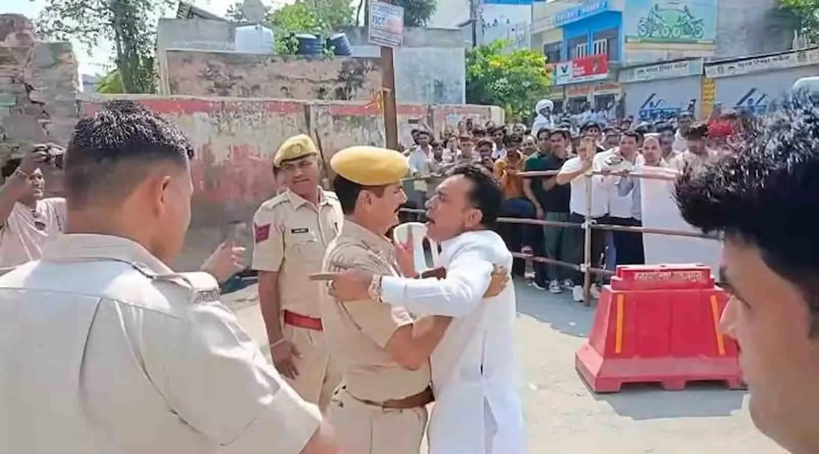 तस्वीर में पुलिसकर्मी सड़क पर सफेद कुर्ता पहने एक व्यक्ति को रोकते हुए नजर आ रहे हैं। तस्वीर में पुलिसकर्मी सड़क पर सफेद कुर्ता पहने एक व्यक्ति को रोकते हुए नजर आ रहे हैं।