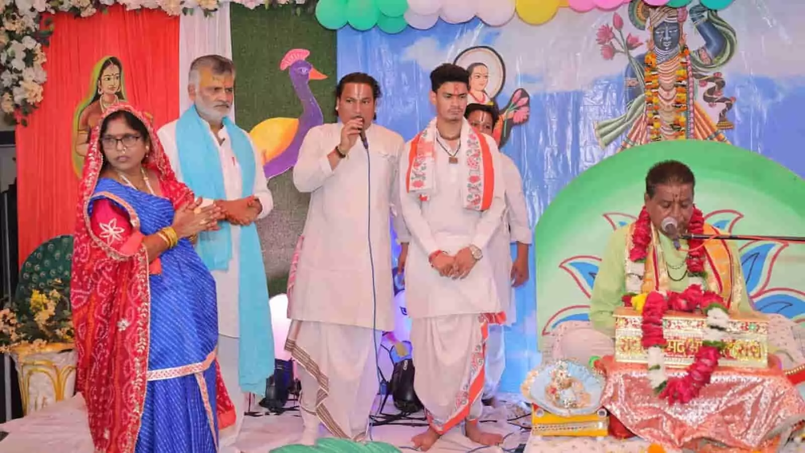 तस्वीर में बाएं से दाएं एक महिला, खड़े हुए पुरुष और दाहिनी ओर व्यास पीठ पर बैठे महाराज नजर आ रहे हैं। तस्वीर में बाएं से दाएं एक महिला, खड़े हुए पुरुष और दाहिनी ओर व्यास पीठ पर बैठे महाराज नजर आ रहे हैं।