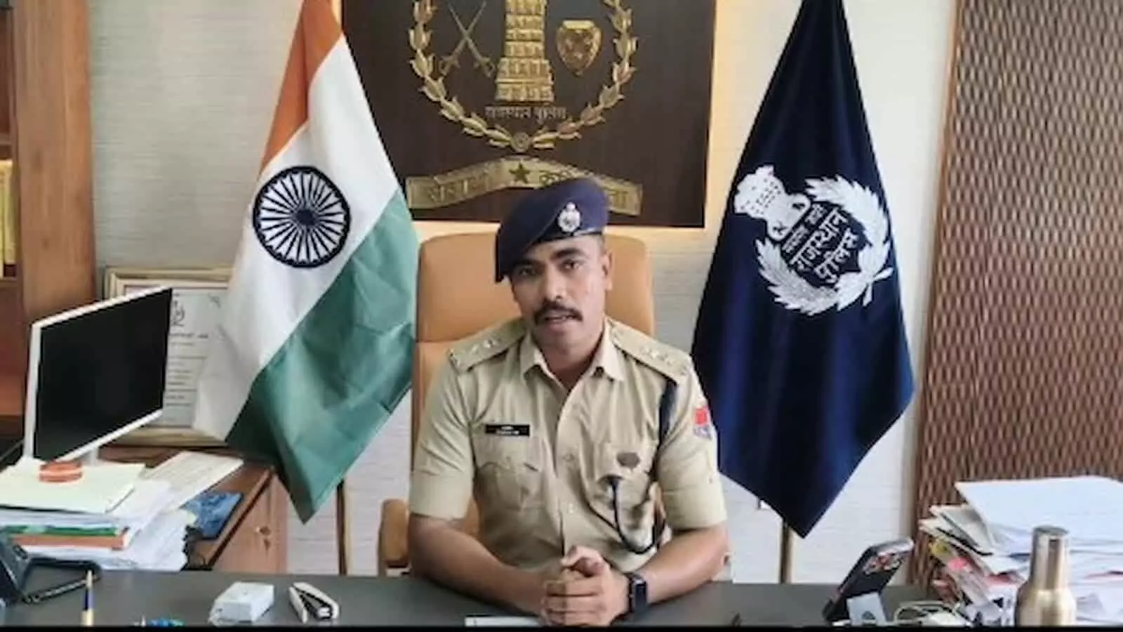तस्वीर में एक पुलिस अधिकारी कार्यालय की मेज पर बैठे हैं, जिनके पीछे भारत का राष्ट्रीय ध्वज और राजस्थान पुलिस का ध्वज रखा है। तस्वीर में एक पुलिस अधिकारी कार्यालय की मेज पर बैठे हैं, जिनके पीछे भारत का राष्ट्रीय ध्वज और राजस्थान पुलिस का ध्वज रखा है।