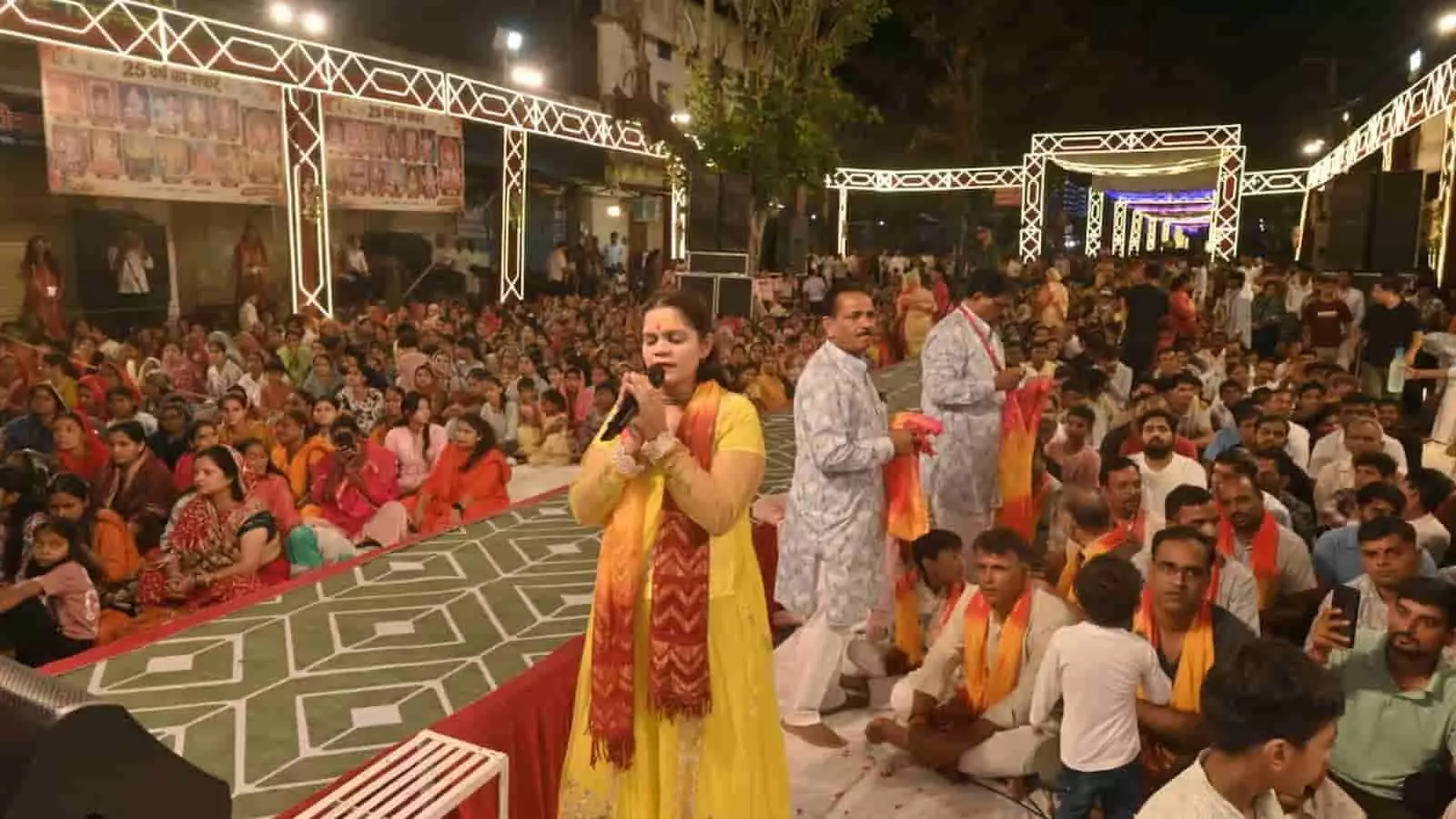 तस्वीर में एक महिला मंच पर माइक के सामने खड़ी होकर गा रही है और सामने बड़ी संख्या में लोग बैठे हैं। तस्वीर में एक महिला मंच पर माइक के सामने खड़ी होकर गा रही है और सामने बड़ी संख्या में लोग बैठे हैं।