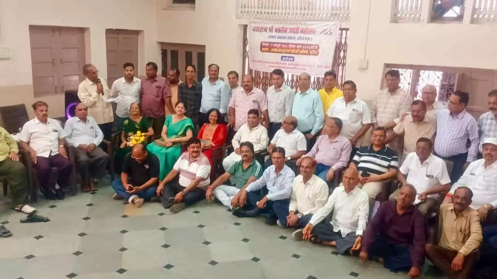तस्वीर में एक बड़े कमरे में बैठे और खड़े हुए कई लोग नजर आ रहे हैं, जिनके पीछे बैनर लगा है। तस्वीर में एक बड़े कमरे में बैठे और खड़े हुए कई लोग नजर आ रहे हैं, जिनके पीछे बैनर लगा है।