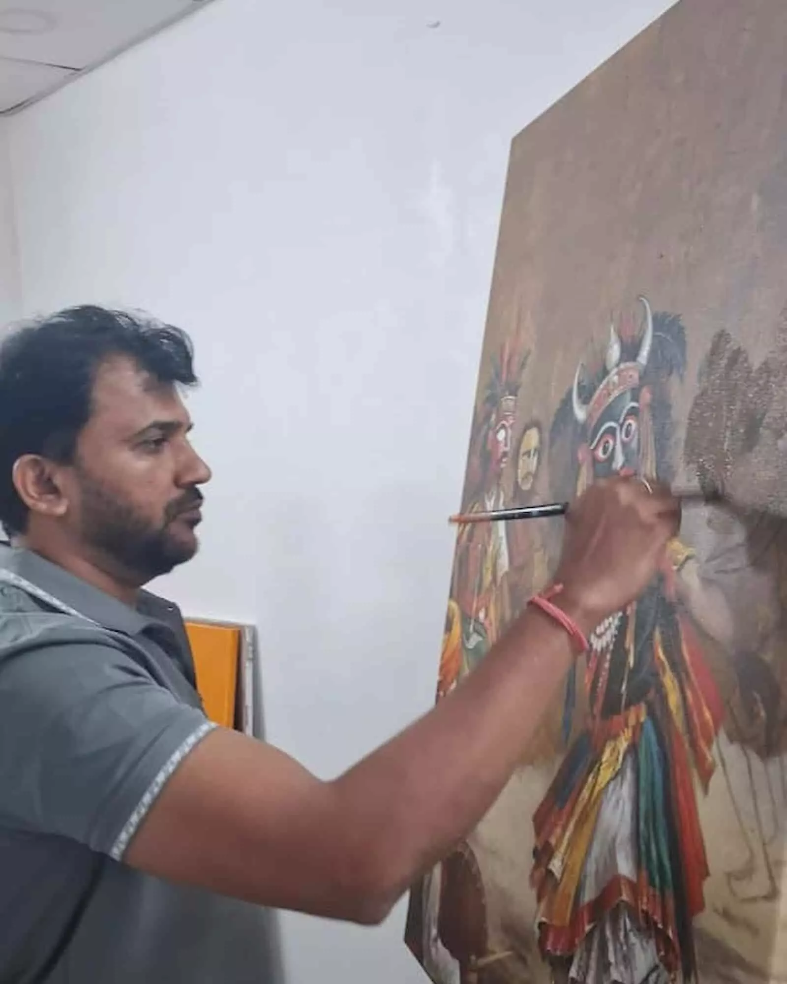 तस्वीर में बाईं ओर खड़े चित्रकार कैनवास बोर्ड पर पारंपरिक वेशभूषा वाली आकृति चित्रित कर रहे हैं। तस्वीर में बाईं ओर खड़े चित्रकार कैनवास बोर्ड पर पारंपरिक वेशभूषा वाली आकृति चित्रित कर रहे हैं।