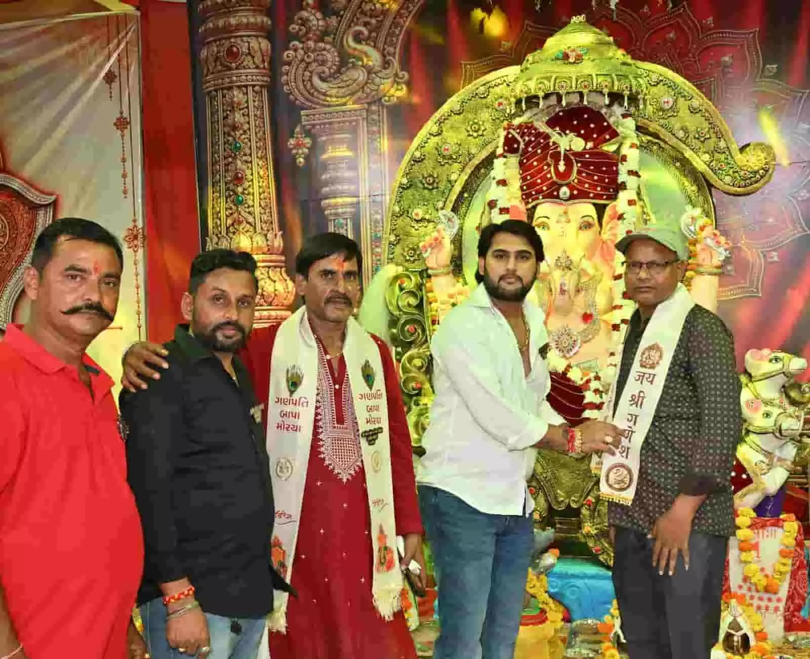 तस्वीर में बाईं से दाईं ओर खड़े पुरुष गणेश पंडाल में एक व्यक्ति को धार्मिक दुपट्टा पहनाते दिख रहे हैं। तस्वीर में बाईं से दाईं ओर खड़े पुरुष गणेश पंडाल में एक व्यक्ति को धार्मिक दुपट्टा पहनाते दिख रहे हैं।