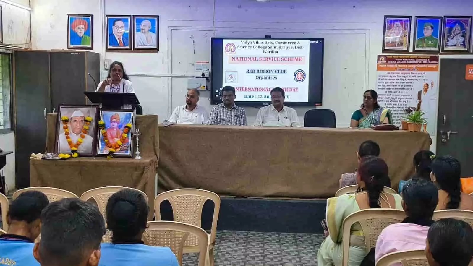 तस्वीर में एक महिला वक्ता मंच पर पोडियम के पास खड़े होकर सामने बैठे विद्यार्थियों को संबोधित कर रही हैं। तस्वीर में एक महिला वक्ता मंच पर पोडियम के पास खड़े होकर सामने बैठे विद्यार्थियों को संबोधित कर रही हैं।