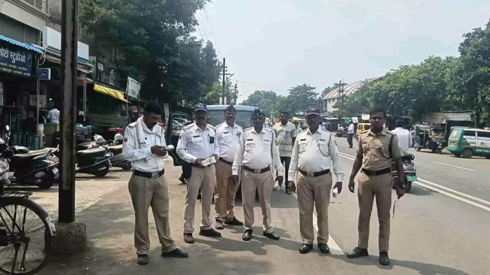 तस्वीर में यातायात पुलिस और सुरक्षाकर्मी सड़क के पास खड़े होकर वाहनों की जांच कर रहे हैं। तस्वीर में यातायात पुलिस और सुरक्षाकर्मी सड़क के पास खड़े होकर वाहनों की जांच कर रहे हैं।