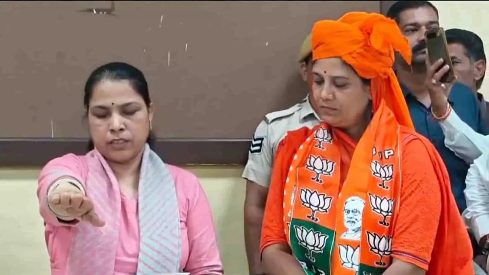 तस्वीर में बाएं हाथ उठाए महिला शपथ ले रही हैं और उनके पास भगवा दुपट्टा पहने जसवंत कंवर बैठी हैं। तस्वीर में बाएं हाथ उठाए महिला शपथ ले रही हैं और उनके पास भगवा दुपट्टा पहने जसवंत कंवर बैठी हैं।