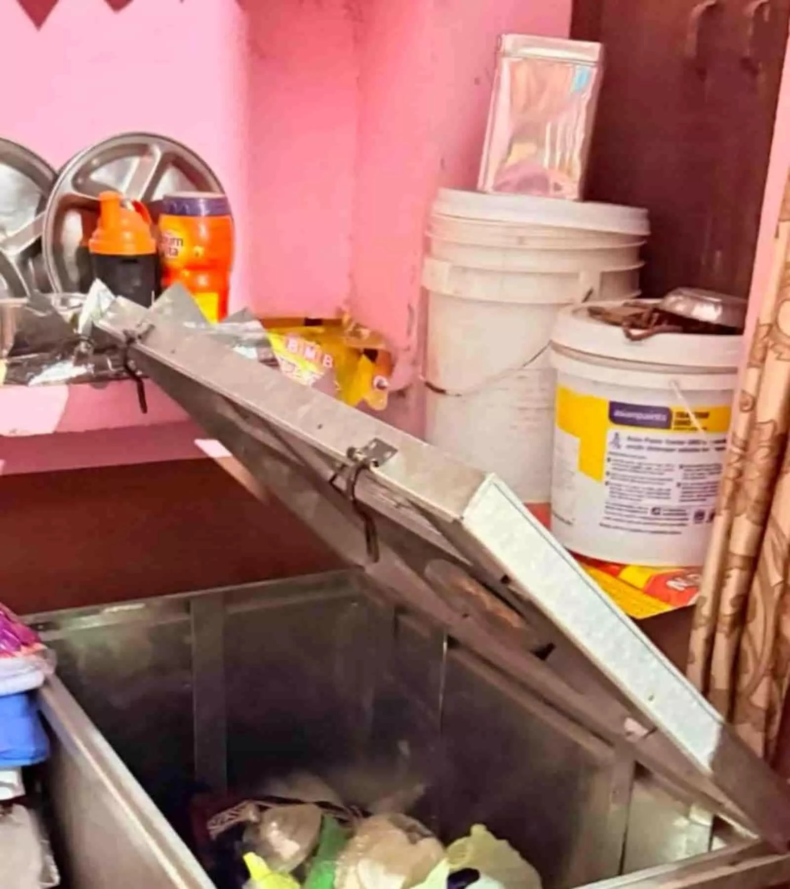 कमरे में रखा हुआ खुला धातु का ट्रंक और आसपास बिखरा हुआ घरेलू सामान। कमरे में रखा हुआ खुला धातु का ट्रंक और आसपास बिखरा हुआ घरेलू सामान।