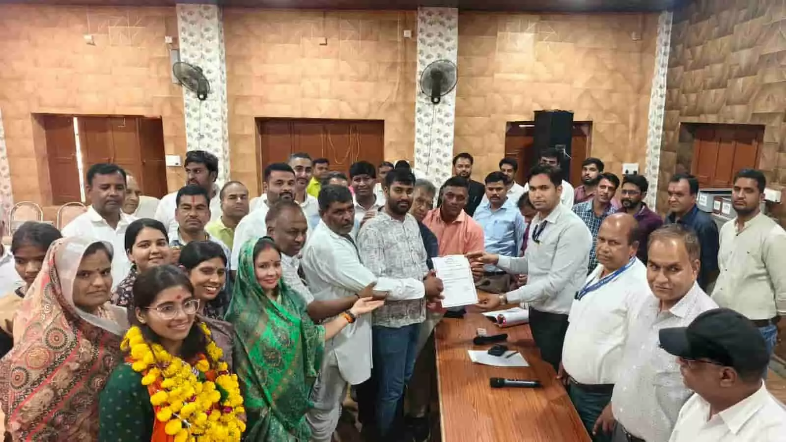 तस्वीर में अधिकारी जीत का प्रमाणपत्र सौंप रहे हैं और आसपास कई लोग खड़े दिखाई दे रहे हैं। तस्वीर में अधिकारी जीत का प्रमाणपत्र सौंप रहे हैं और आसपास कई लोग खड़े दिखाई दे रहे हैं।