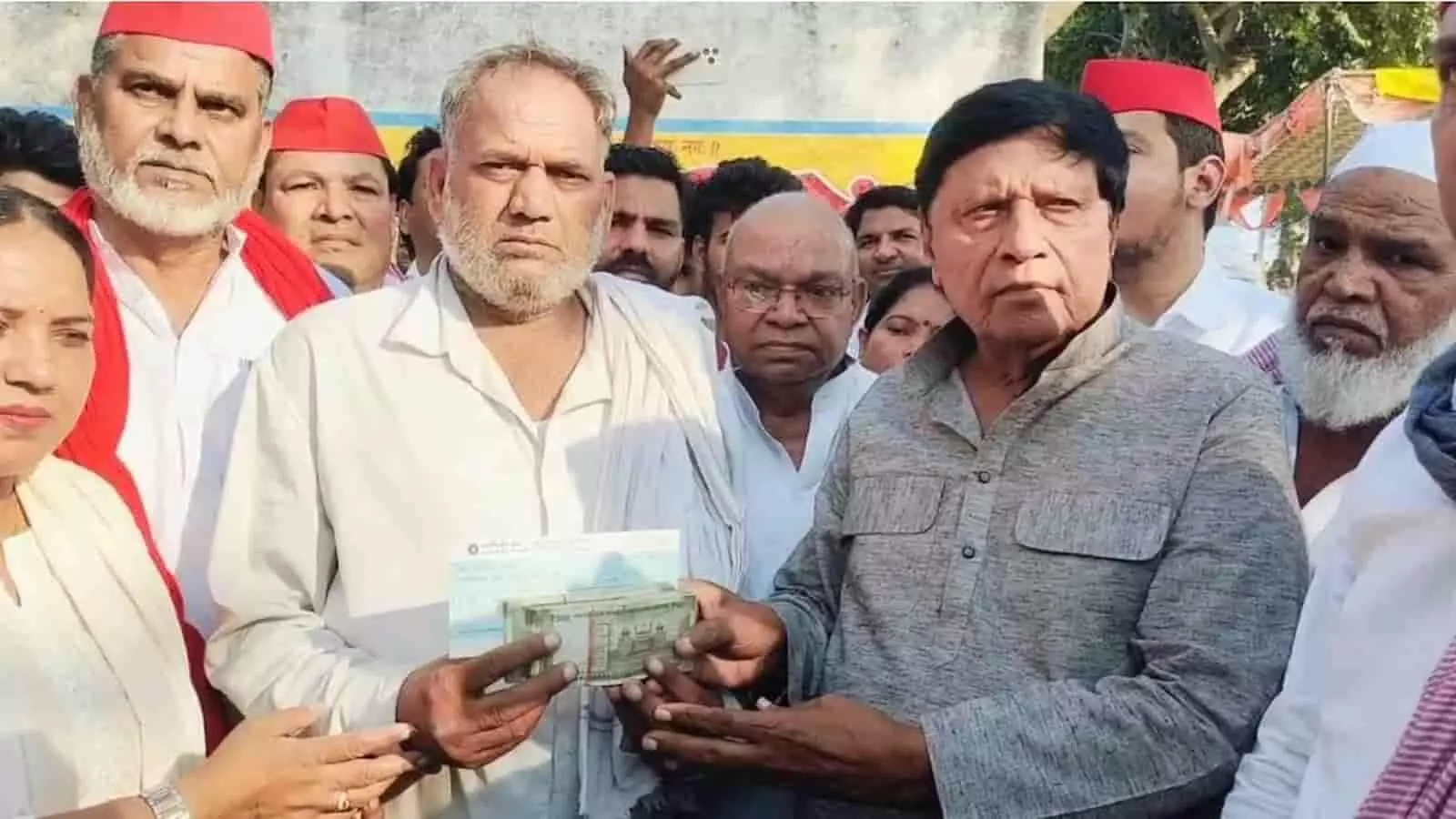 तस्वीर में बाएं से दाएं खड़े व्यक्ति और सपा सांसद रामजीलाल सुमन नकदी व चेक हाथों में थामे दिख रहे हैं। तस्वीर में बाएं से दाएं खड़े व्यक्ति और सपा सांसद रामजीलाल सुमन नकदी व चेक हाथों में थामे दिख रहे हैं।