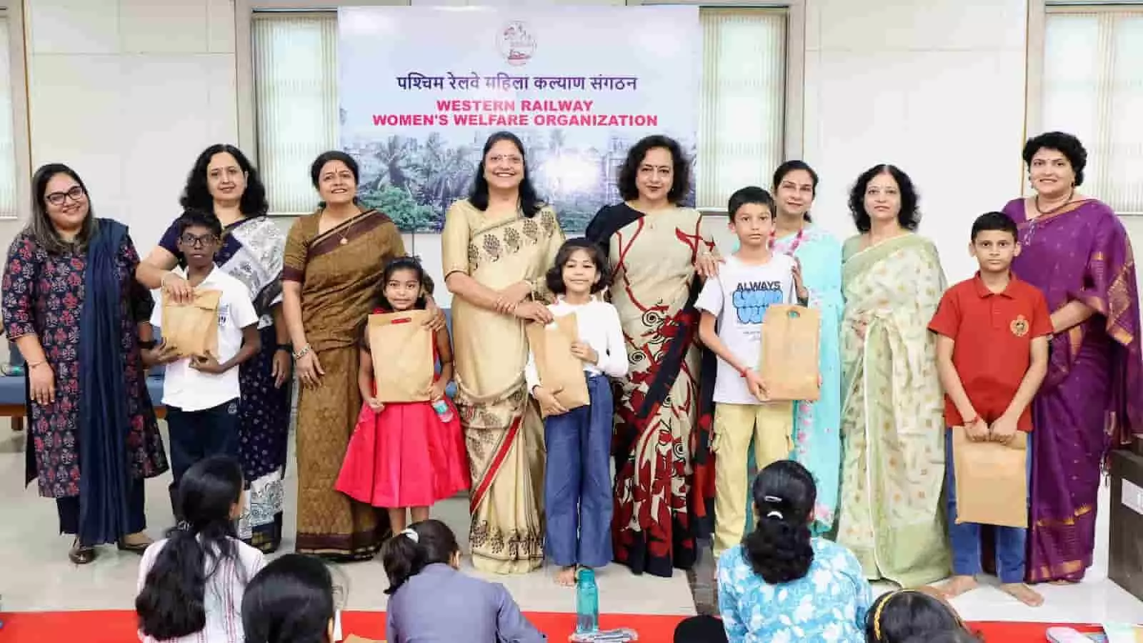 तस्वीर में दिख रही WRWWO की कार्यकारी समिति की सदस्य बच्चों के साथ उपहार सामग्री के साथ खड़ी हैं। तस्वीर में दिख रही WRWWO की कार्यकारी समिति की सदस्य बच्चों के साथ उपहार सामग्री के साथ खड़ी हैं।