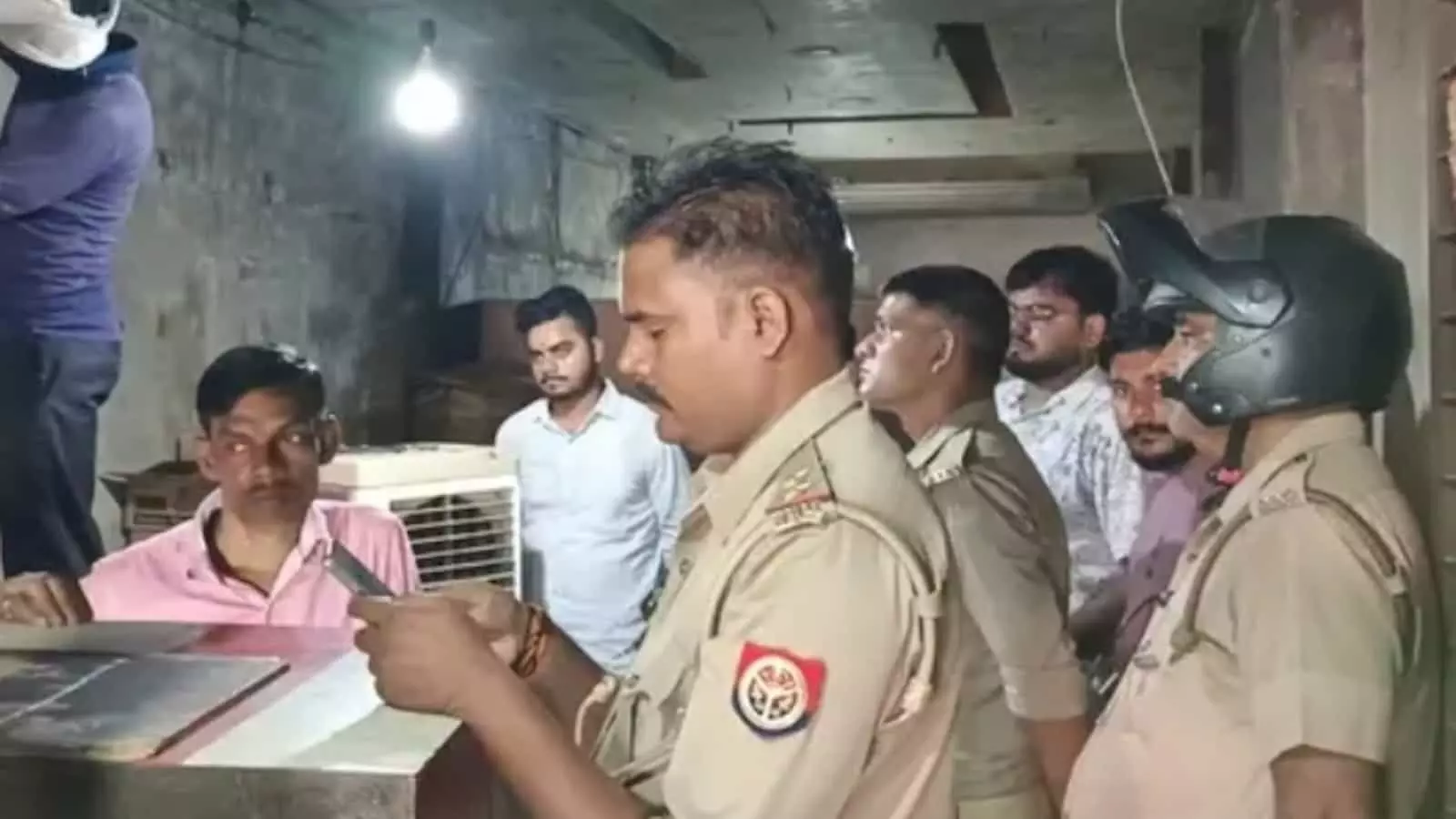 तस्वीर में बाएं से दाएं बैठे व्यक्ति और पुलिस कर्मी दुकान के अंदर जांच करते दिख रहे हैं। तस्वीर में बाएं से दाएं बैठे व्यक्ति और पुलिस कर्मी दुकान के अंदर जांच करते दिख रहे हैं।