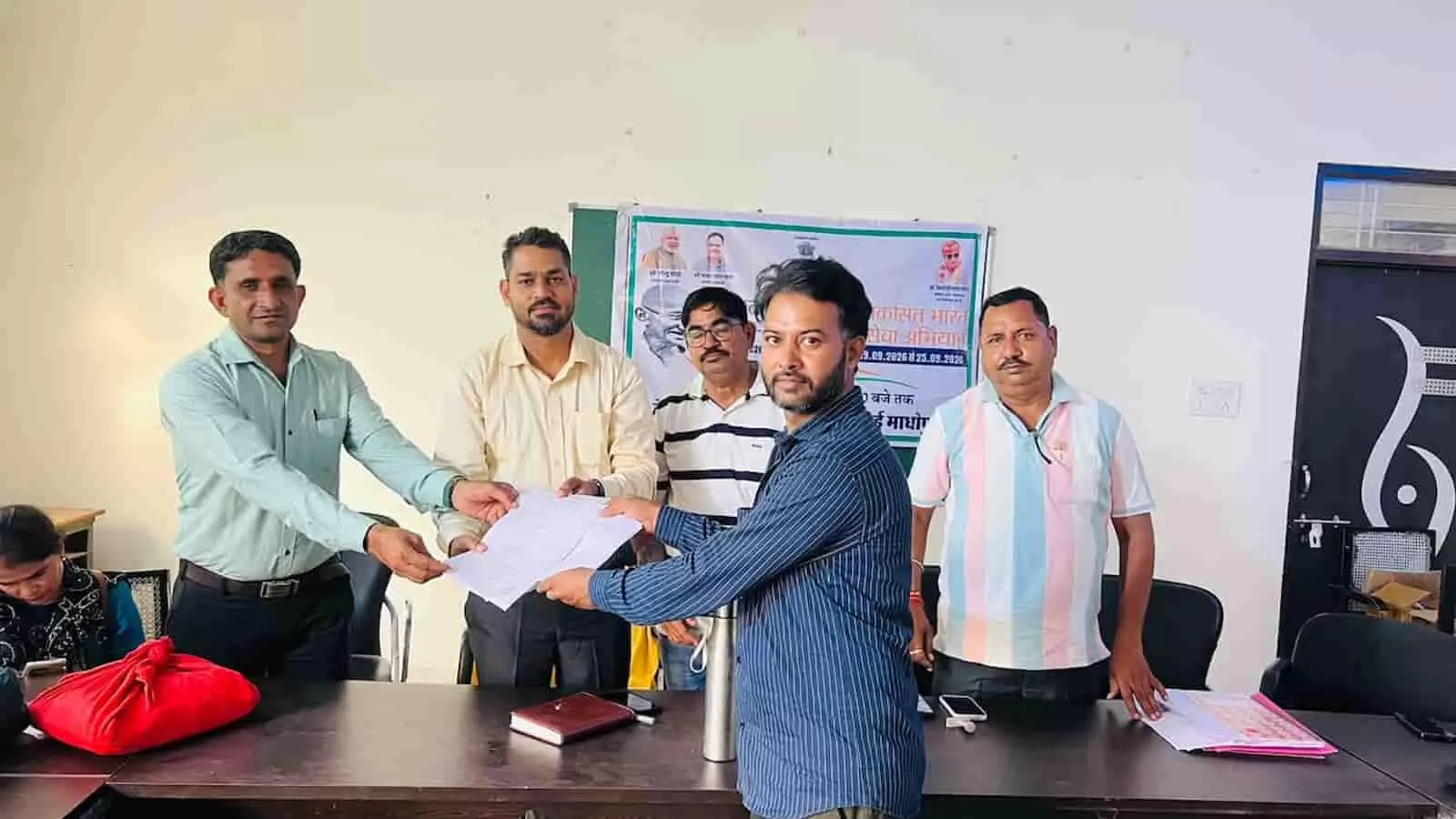 तस्वीर में अधिकारी एक व्यक्ति को दस्तावेज थमाते नजर आ रहे हैं। तस्वीर में अधिकारी एक व्यक्ति को दस्तावेज थमाते नजर आ रहे हैं।
