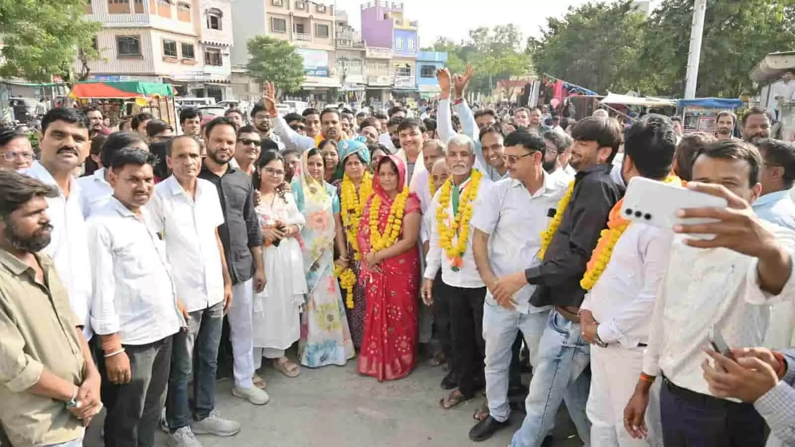 तस्वीर में माला पहने महिला और पुरुषों के साथ बड़ी सादड़ी में लोगों का समूह खड़ा दिखाई दे रहा है। तस्वीर में माला पहने महिला और पुरुषों के साथ बड़ी सादड़ी में लोगों का समूह खड़ा दिखाई दे रहा है।