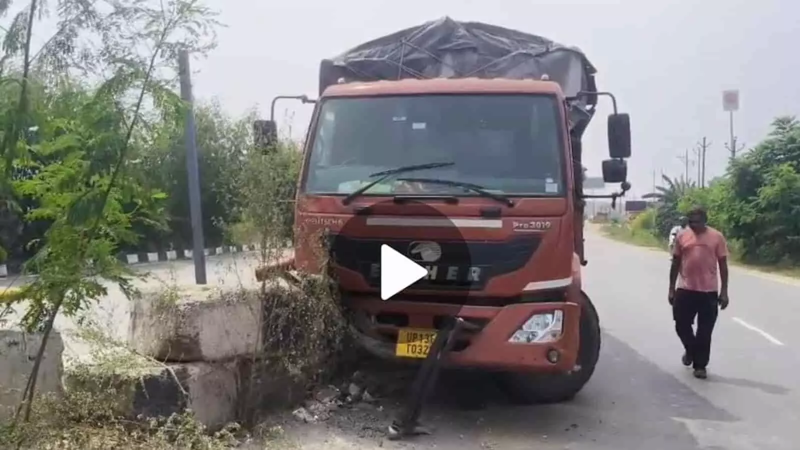 हाईवे पर डिवाइडर से टकराकर खड़ा एक लाल रंग का कैंटर और सड़क पर चलता व्यक्ति। हाईवे पर डिवाइडर से टकराकर खड़ा एक लाल रंग का कैंटर और सड़क पर चलता व्यक्ति।