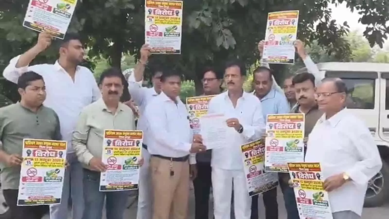 तस्वीर में दिख रहे व्यापारी पोस्टर लहराते हुए और एक-दूसरे को पत्र सौंपते हुए विरोध जता रहे हैं। तस्वीर में दिख रहे व्यापारी पोस्टर लहराते हुए और एक-दूसरे को पत्र सौंपते हुए विरोध जता रहे हैं।