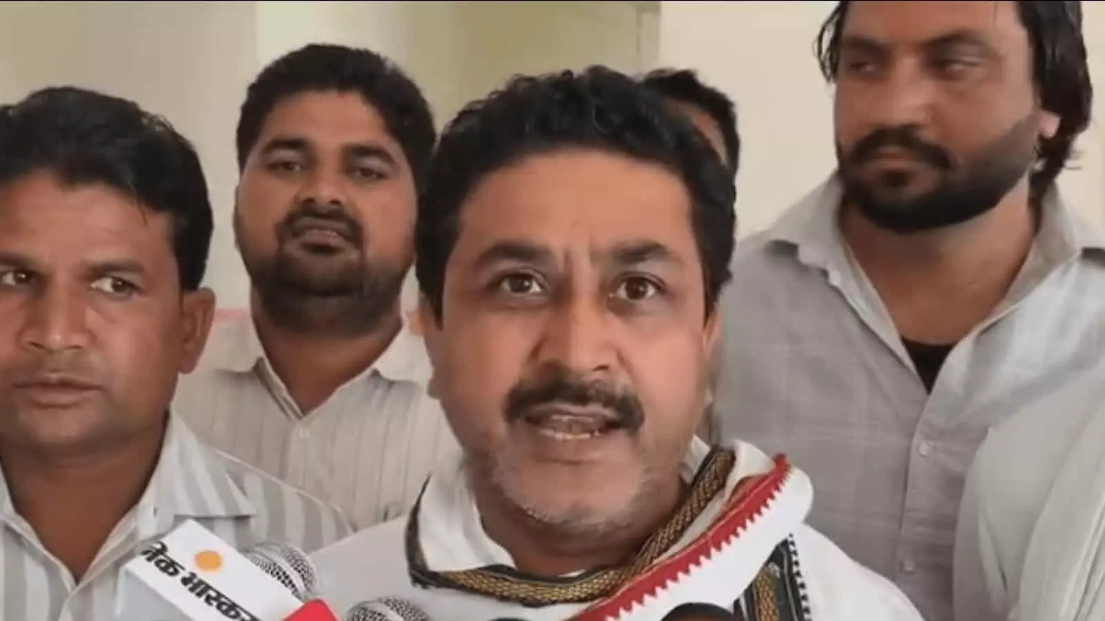 तस्वीर में आगे खड़े एक नेता माइक के सामने बात कर रहे हैं और उनके पीछे कई लोग खड़े हुए हैं। तस्वीर में आगे खड़े एक नेता माइक के सामने बात कर रहे हैं और उनके पीछे कई लोग खड़े हुए हैं।