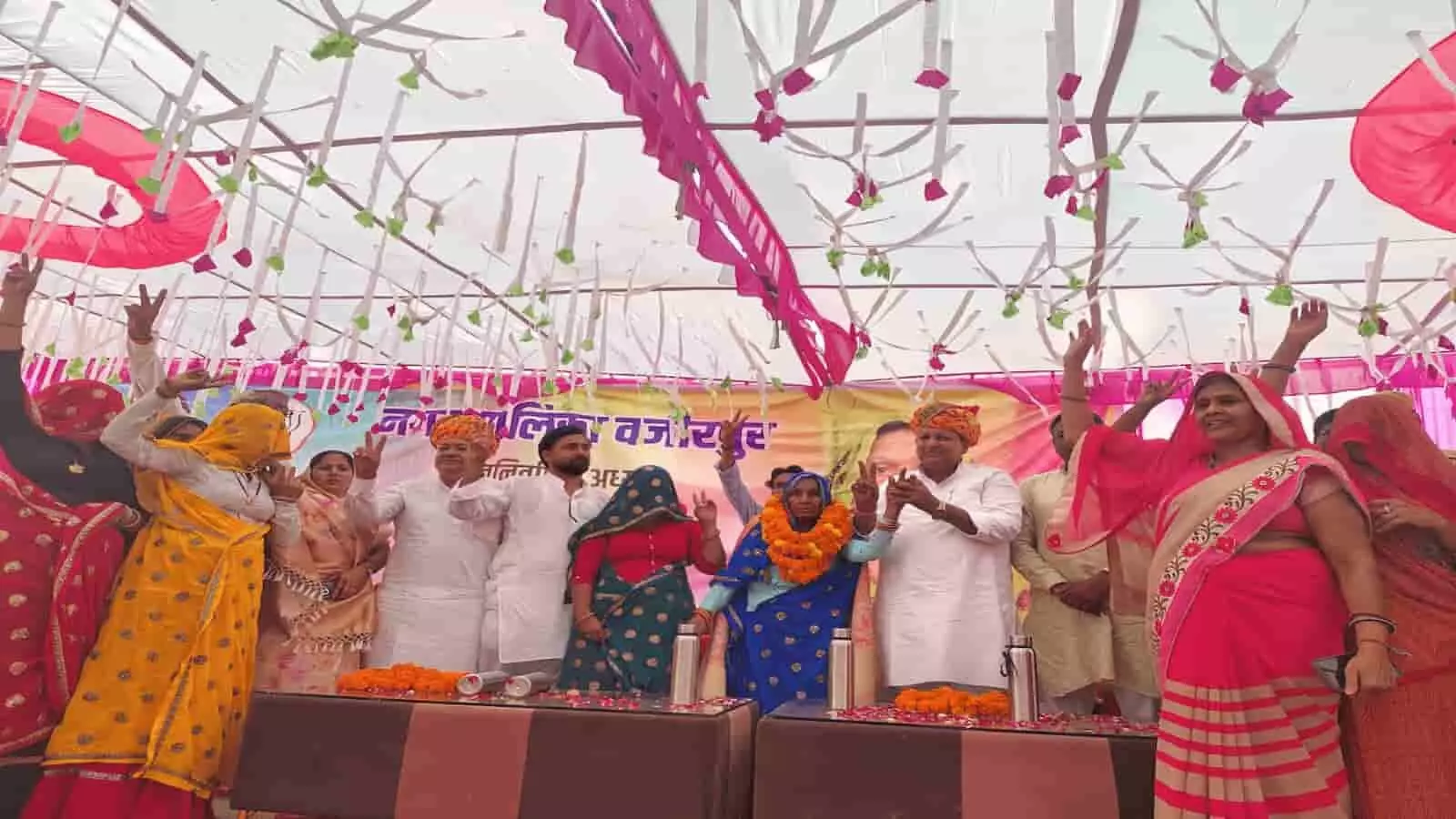 तस्वीर में वजीरपुर नगर पालिका के कार्यक्रम के दौरान मंच पर खड़े लोग हाथ उठाकर अभिवादन कर रहे हैं और महिलाएं साड़ियों में नजर आ रही हैं। तस्वीर में वजीरपुर नगर पालिका के कार्यक्रम के दौरान मंच पर खड़े लोग हाथ उठाकर अभिवादन कर रहे हैं और महिलाएं साड़ियों में नजर आ रही हैं।