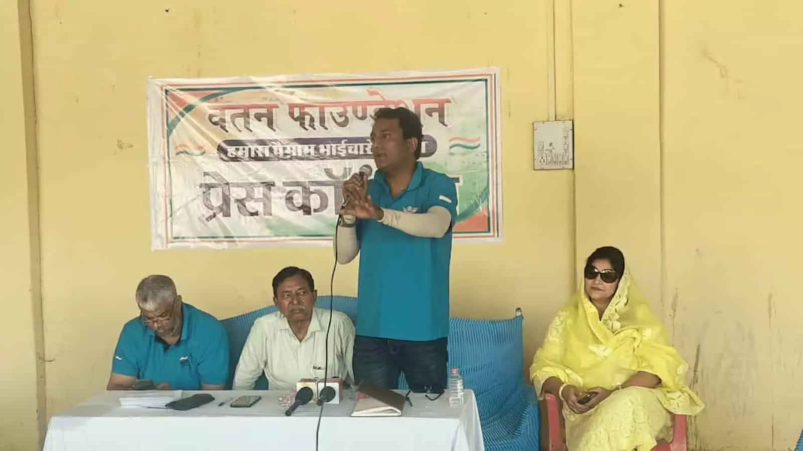 तस्वीर में एक बैनर के सामने खड़े होकर वतन फाउंडेशन के प्रवक्ता माइक से बात कर रहे हैं और उनके पास अन्य लोग बैठे हैं। तस्वीर में एक बैनर के सामने खड़े होकर वतन फाउंडेशन के प्रवक्ता माइक से बात कर रहे हैं और उनके पास अन्य लोग बैठे हैं।