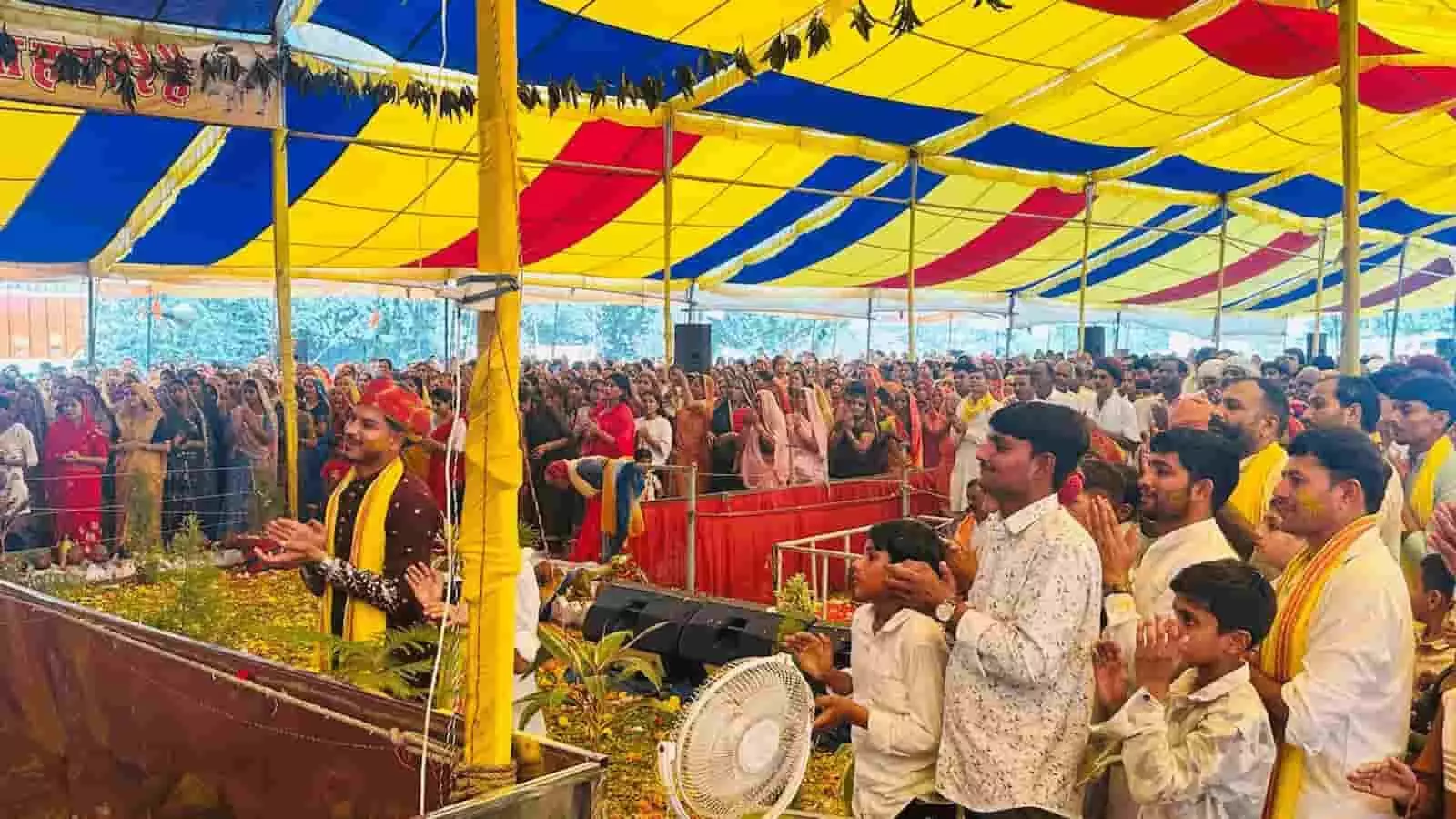तस्वीर में एक भव्य धार्मिक पंडाल के नीचे बड़ी संख्या में बैठे हुए श्रद्धालु हाथ जोड़कर कथा का श्रवण कर रहे हैं। तस्वीर में एक भव्य धार्मिक पंडाल के नीचे बड़ी संख्या में बैठे हुए श्रद्धालु हाथ जोड़कर कथा का श्रवण कर रहे हैं।