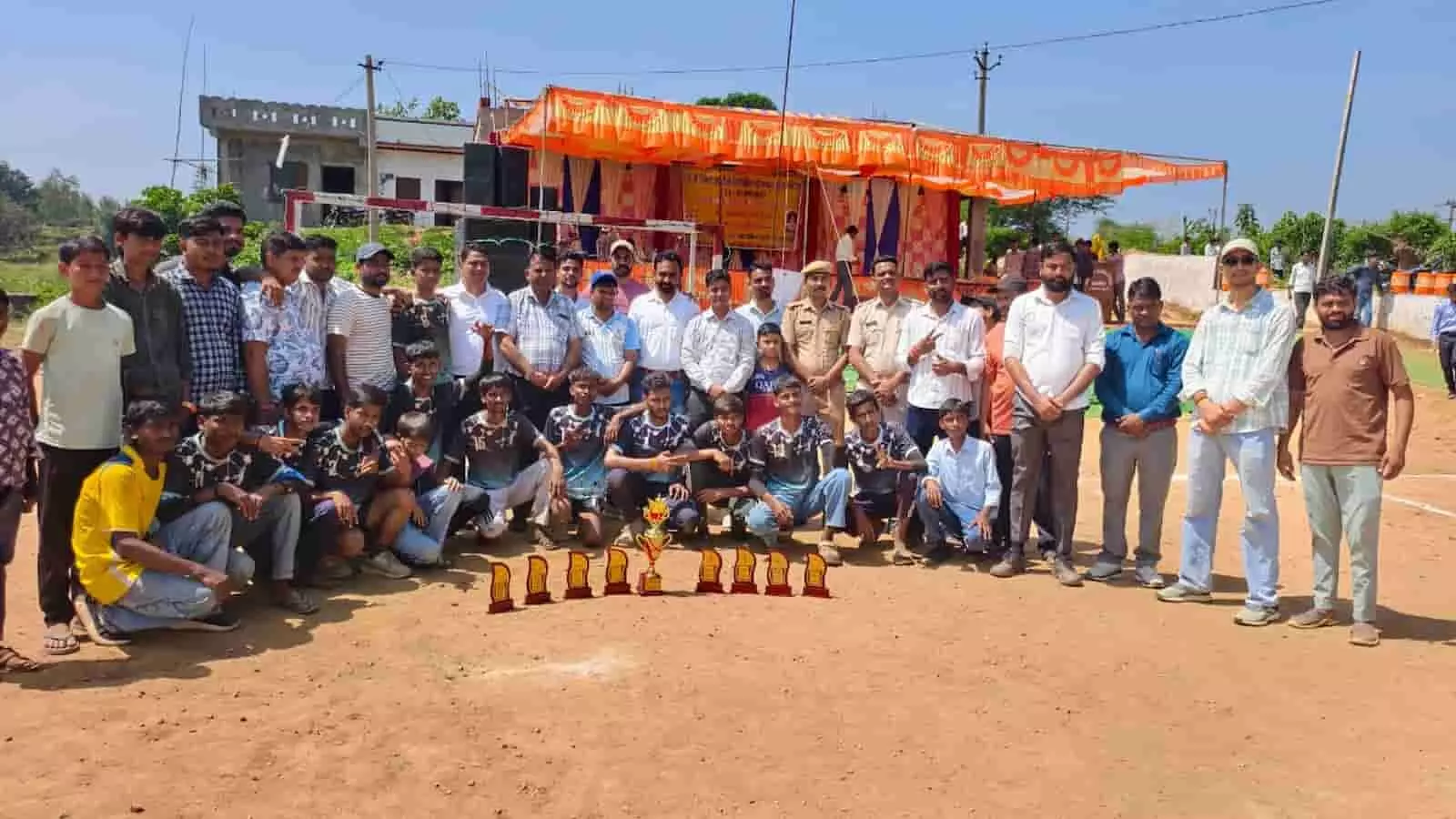 तस्वीर में दिख रही टीम और अतिथि मैदान में रखी ट्रॉफी के पीछे सामूहिक तस्वीर खिंचवा रहे हैं। तस्वीर में दिख रही टीम और अतिथि मैदान में रखी ट्रॉफी के पीछे सामूहिक तस्वीर खिंचवा रहे हैं।