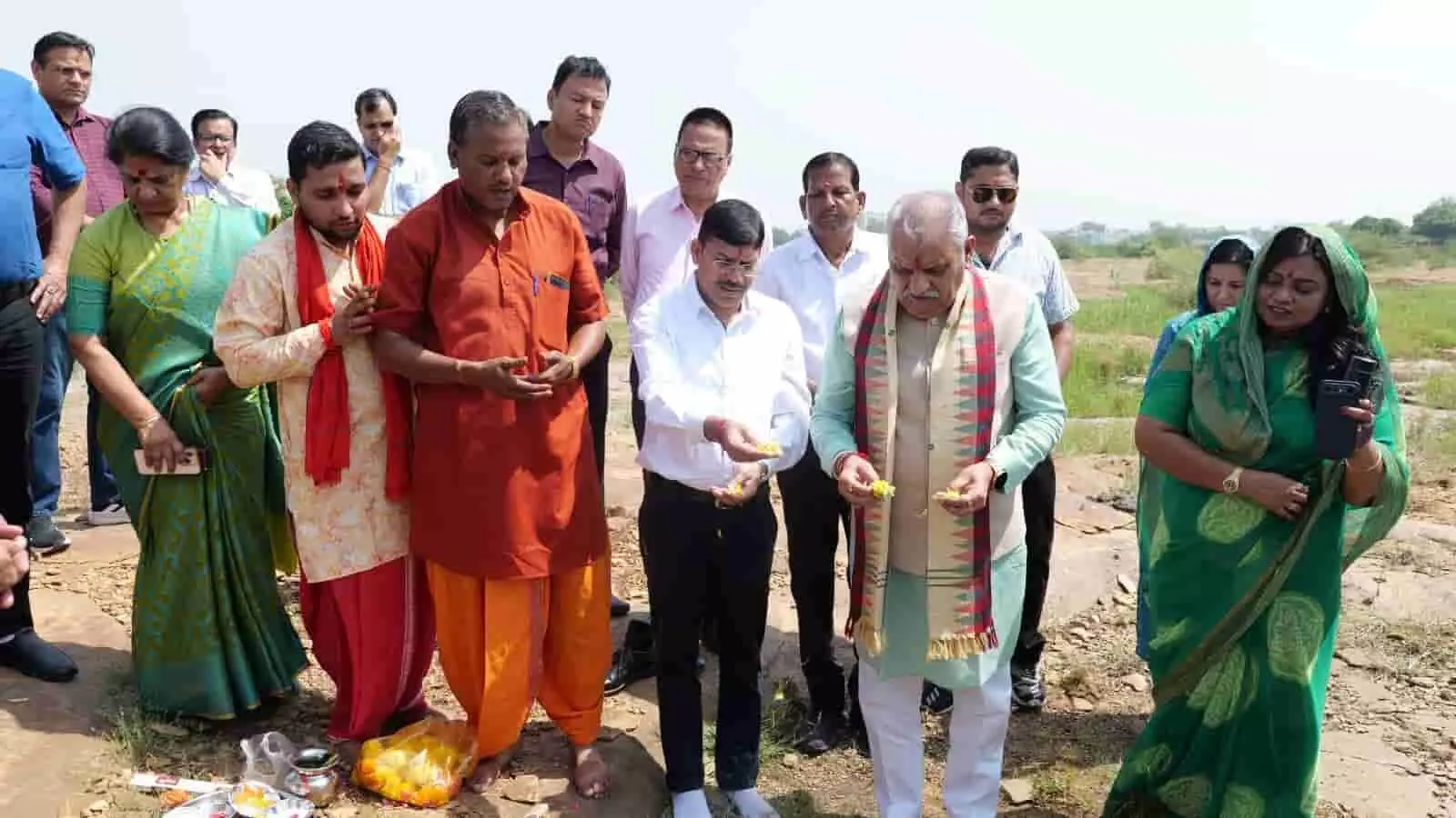 कोटा विश्वविद्यालय के परिसर में खुले मैदान में खड़े लोग हाथों में फूल लेकर भूमि पूजन कर रहे हैं। कोटा विश्वविद्यालय के परिसर में खुले मैदान में खड़े लोग हाथों में फूल लेकर भूमि पूजन कर रहे हैं।