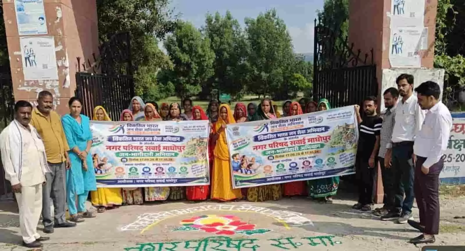 तस्वीर में दिख रही एक मुख्य गेट के सामने खड़े होकर विकसित भारत अभियान का बैनर पकड़े महिलाओं और पुरुषों की टोली। तस्वीर में दिख रही एक मुख्य गेट के सामने खड़े होकर विकसित भारत अभियान का बैनर पकड़े महिलाओं और पुरुषों की टोली।