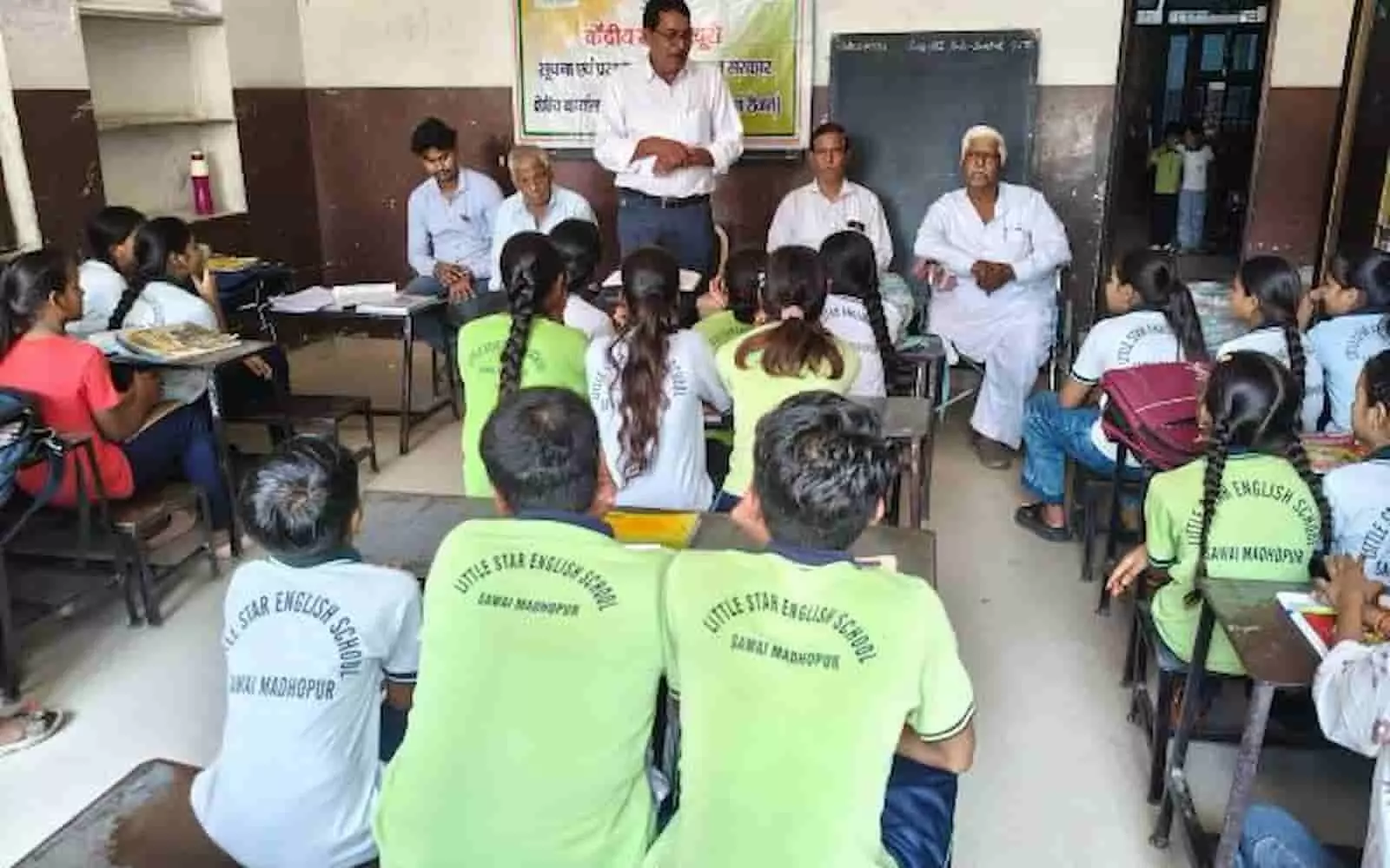 तस्वीर में एक शिक्षक कक्षा में बैठे विद्यार्थियों और अन्य अतिथियों को संबोधित करते हुए दिख रहे हैं। तस्वीर में एक शिक्षक कक्षा में बैठे विद्यार्थियों और अन्य अतिथियों को संबोधित करते हुए दिख रहे हैं।