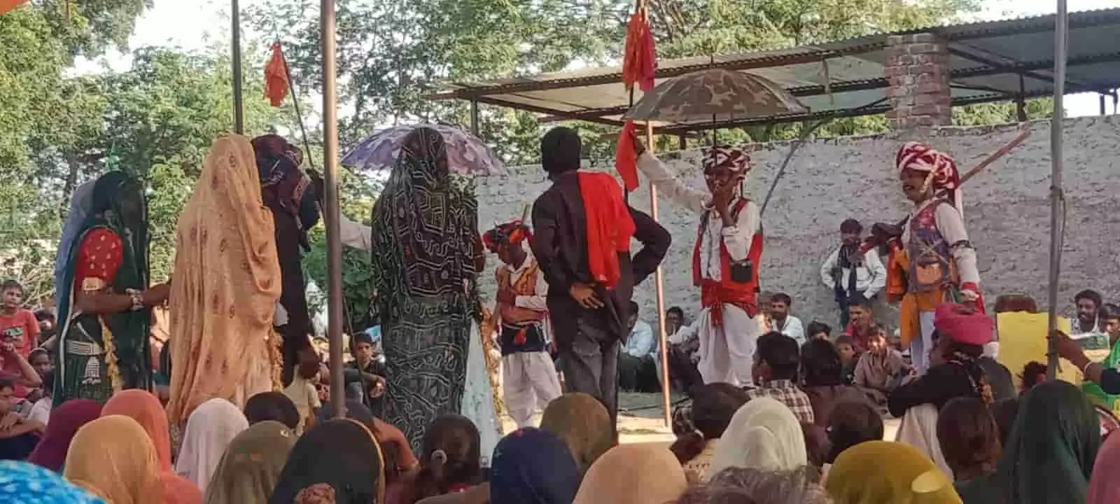 तस्वीर में दिख रही जगह पर लोक कलाकार गवरी नृत्य प्रस्तुत कर रहे हैं और ग्रामीण बैठकर देख रहे हैं। तस्वीर में दिख रही जगह पर लोक कलाकार गवरी नृत्य प्रस्तुत कर रहे हैं और ग्रामीण बैठकर देख रहे हैं।