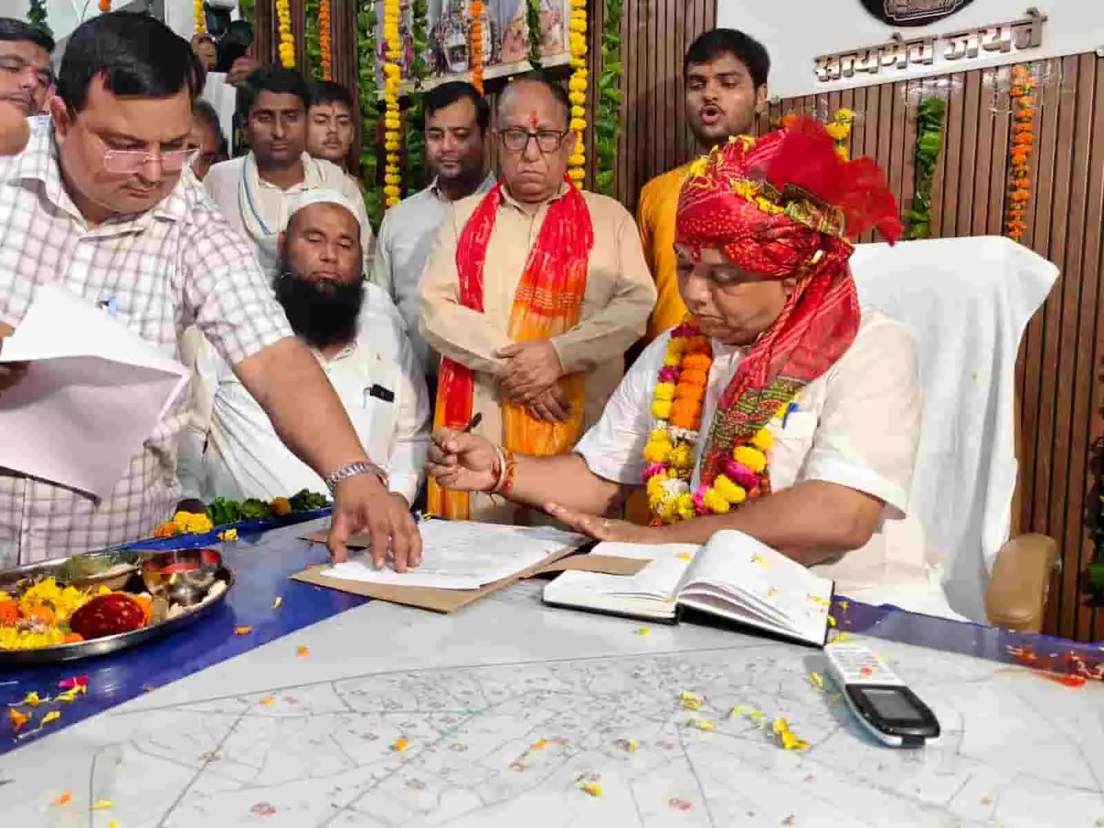 तस्वीर में साफा और माला पहने कृष्ण कुमार गोयल अन्य लोगों की मौजूदगी में मेज पर रखे कागजात पर हस्ताक्षर कर रहे हैं। तस्वीर में साफा और माला पहने कृष्ण कुमार गोयल अन्य लोगों की मौजूदगी में मेज पर रखे कागजात पर हस्ताक्षर कर रहे हैं।
