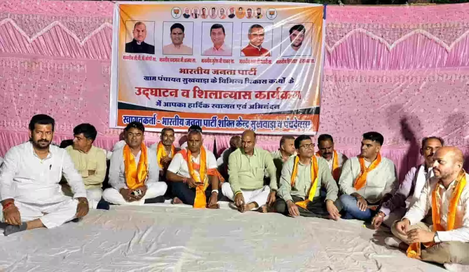 तस्वीर में दिख रही जगह पर जनप्रतिनिधि और ग्रामीण एक बैनर के सामने मंच पर बैठे हैं। तस्वीर में दिख रही जगह पर जनप्रतिनिधि और ग्रामीण एक बैनर के सामने मंच पर बैठे हैं।