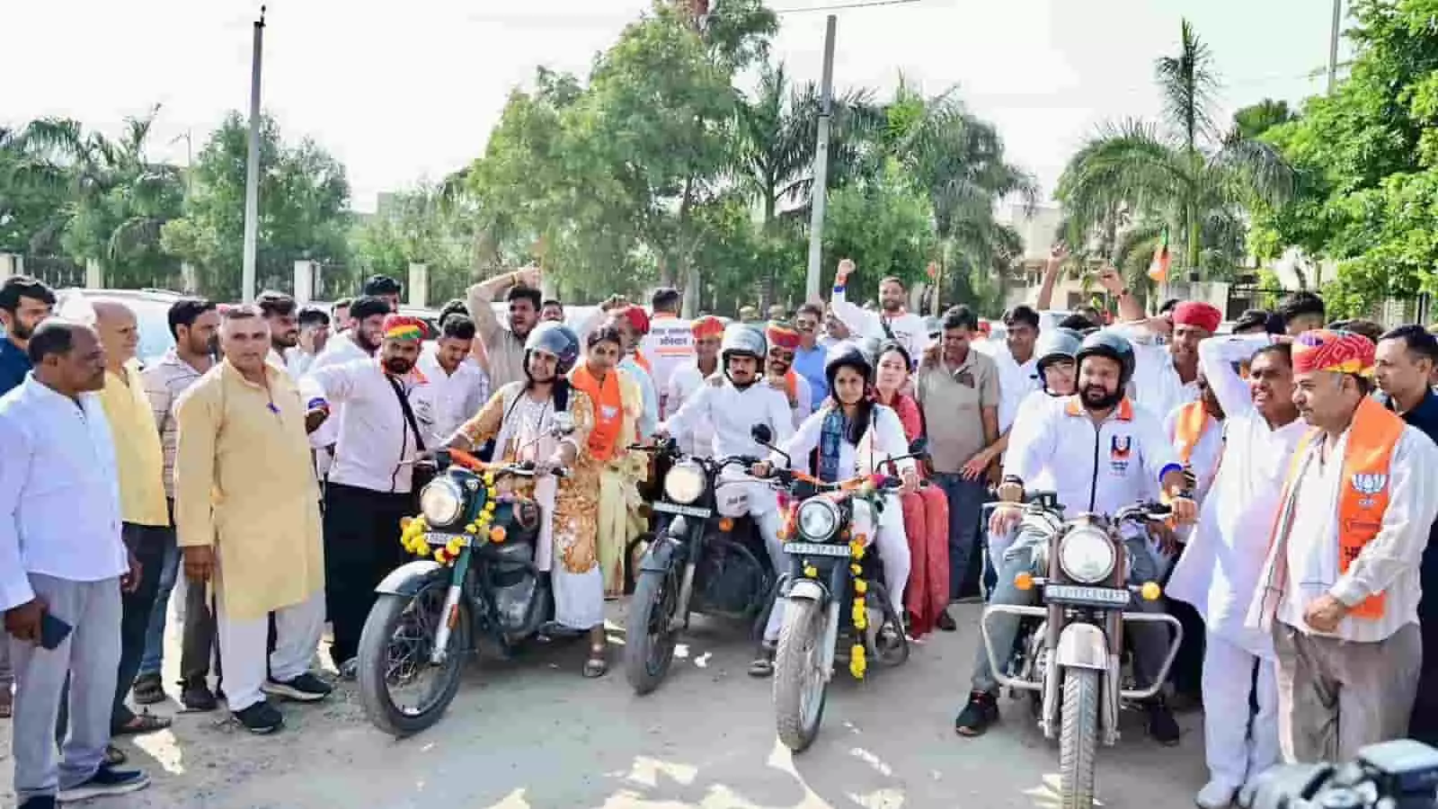 तस्वीर में हाथों में झंडे और नारंगी साफे पहने हुए लोग मोटरसाइकिलों के साथ रैली में दिखाई दे रहे हैं। तस्वीर में हाथों में झंडे और नारंगी साफे पहने हुए लोग मोटरसाइकिलों के साथ रैली में दिखाई दे रहे हैं।