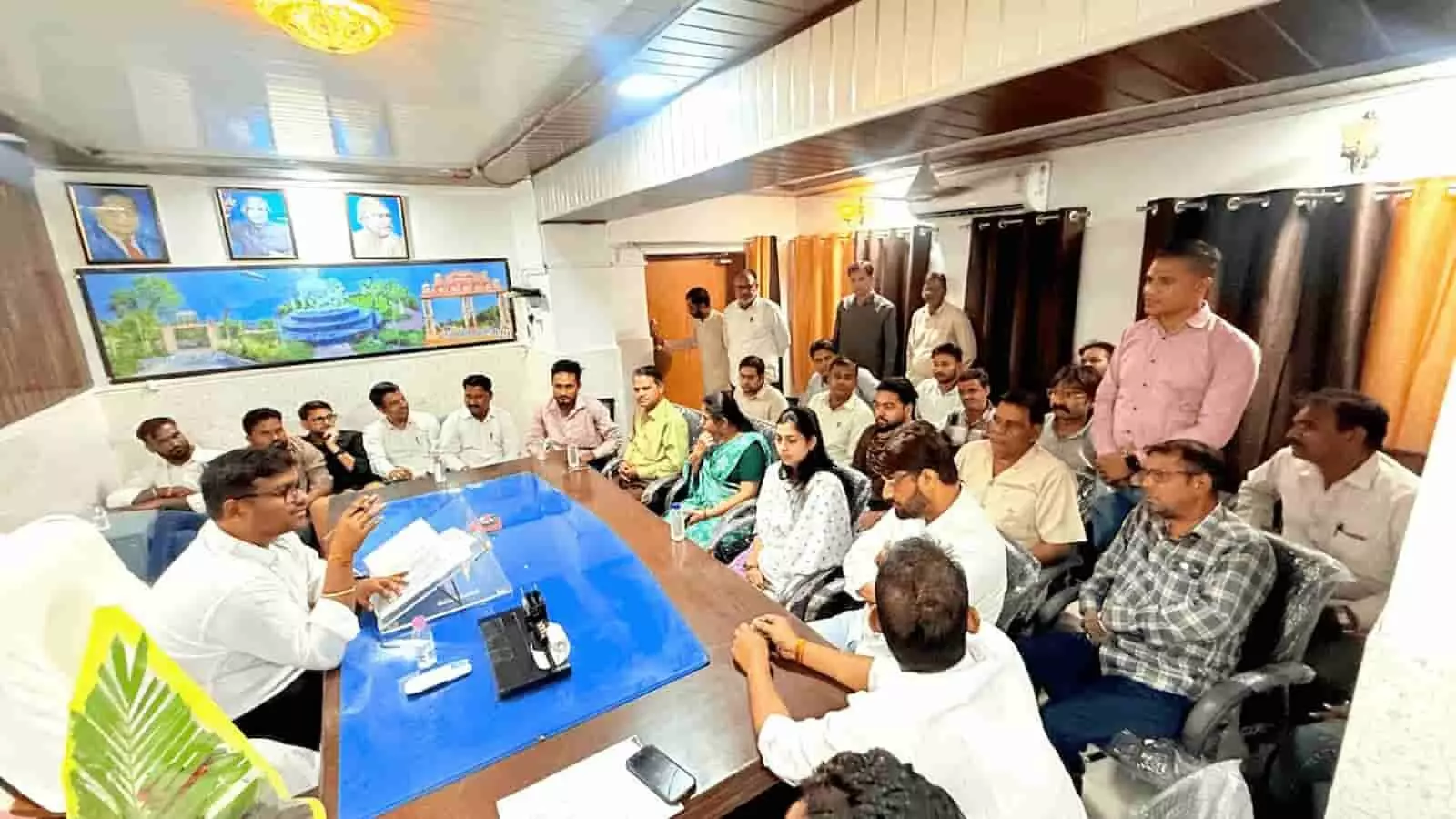 तस्वीर में नगर परिषद के सभागार में मेज के चारों ओर बैठे हुए सभापति और अधिकारी दिखाई दे रहे हैं। तस्वीर में नगर परिषद के सभागार में मेज के चारों ओर बैठे हुए सभापति और अधिकारी दिखाई दे रहे हैं।
