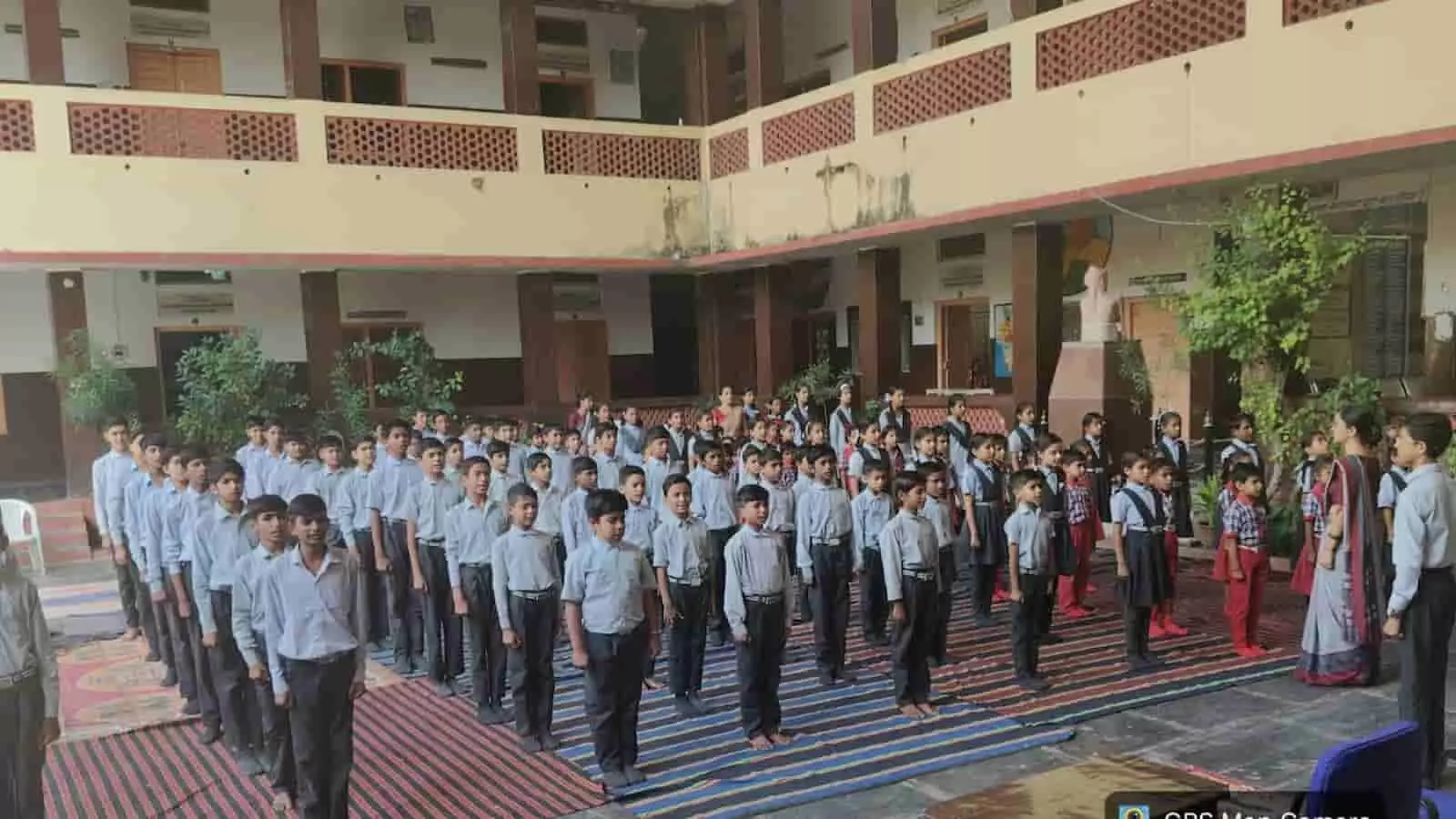 तस्वीर में स्कूल की प्रांगण में पंक्तिबद्ध खड़े हुए छात्र और शिक्षक सामूहिक रूप से गाते हुए दिखाई दे रहे हैं। तस्वीर में स्कूल की प्रांगण में पंक्तिबद्ध खड़े हुए छात्र और शिक्षक सामूहिक रूप से गाते हुए दिखाई दे रहे हैं।