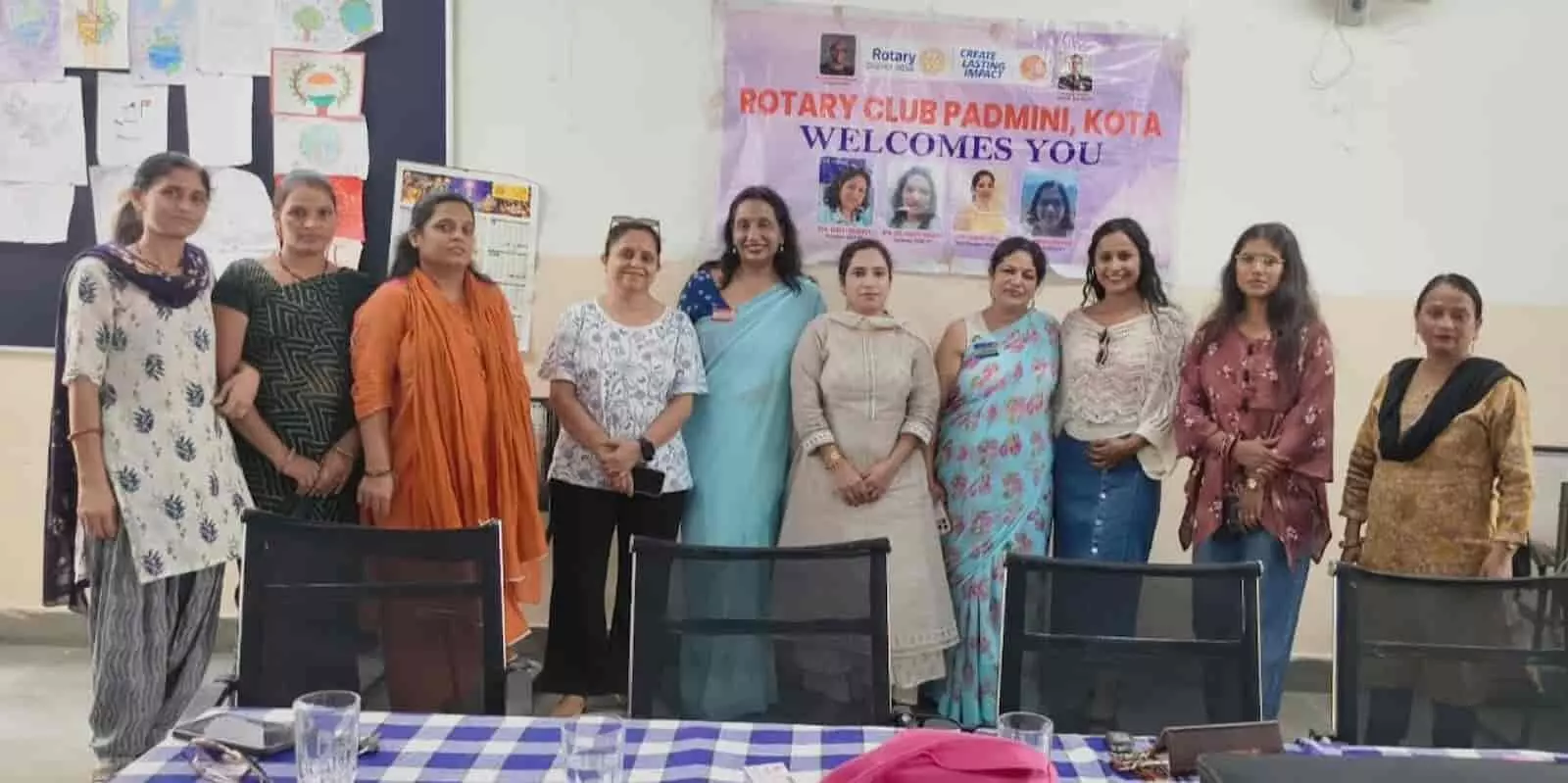 कमरे में बैनर के सामने एक कतार में खड़ी रोटरी क्लब पद्मिनी की महिला सदस्य। कमरे में बैनर के सामने एक कतार में खड़ी रोटरी क्लब पद्मिनी की महिला सदस्य।