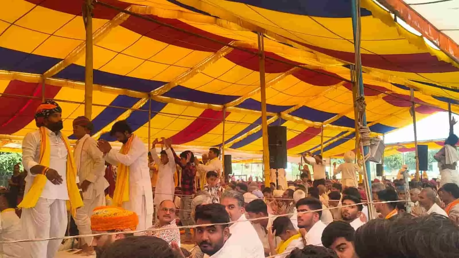 तस्वीर में टेंट के नीचे कथा स्थल पर बैठे हुए पुरुष और बच्चे तथा मंच पर खड़े वक्ता दिखाई दे रहे हैं। तस्वीर में टेंट के नीचे कथा स्थल पर बैठे हुए पुरुष और बच्चे तथा मंच पर खड़े वक्ता दिखाई दे रहे हैं।