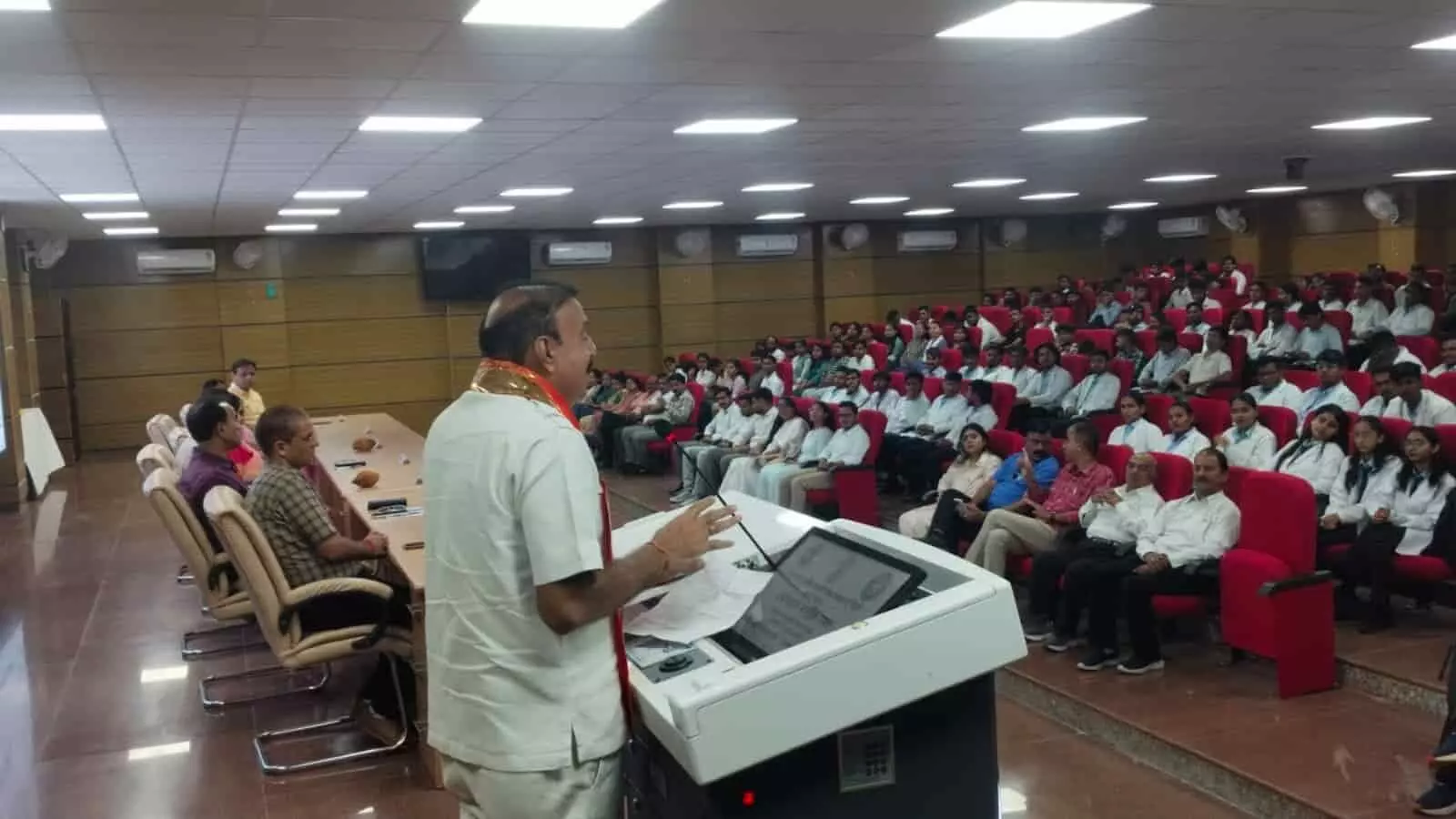 विश्वविद्यालय के ऑडिटोरियम में मंच से बोलते वक्ता और सामने बैठे छात्र तथा अतिथि। विश्वविद्यालय के ऑडिटोरियम में मंच से बोलते वक्ता और सामने बैठे छात्र तथा अतिथि।