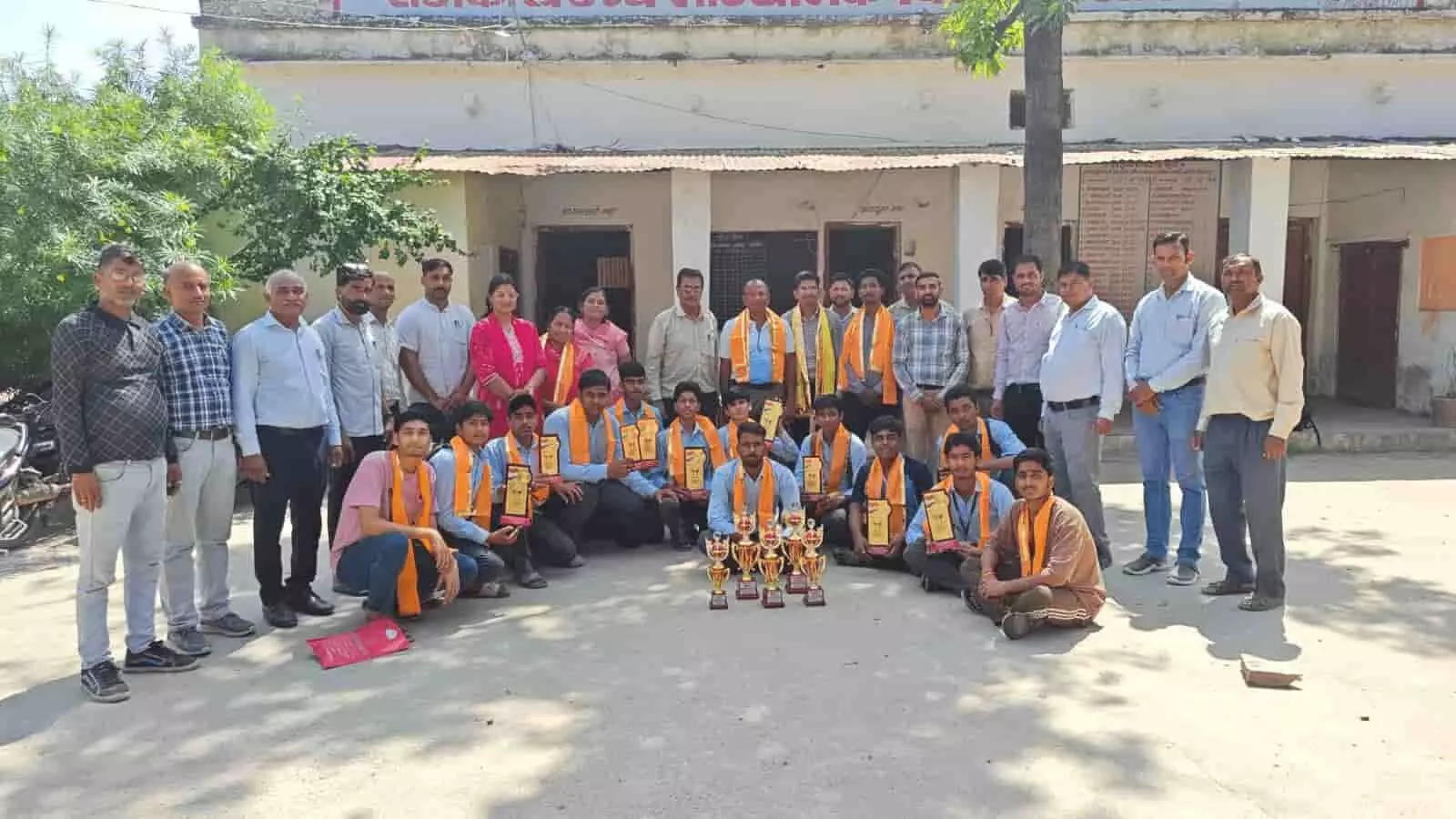 तस्वीर में विद्यालय परिसर में खड़े छात्र और शिक्षक अपने हाथों में विजेता ट्रॉफियां थामे हुए दिखाई दे रहे हैं। तस्वीर में विद्यालय परिसर में खड़े छात्र और शिक्षक अपने हाथों में विजेता ट्रॉफियां थामे हुए दिखाई दे रहे हैं।