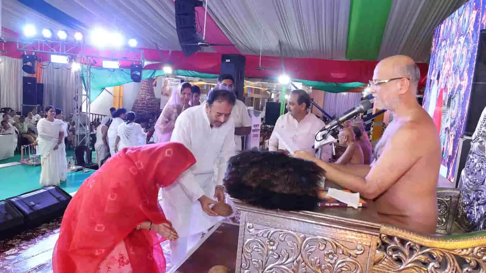 मंच पर विराजमान जैन मुनि के समक्ष सिर झुकाकर फल अर्पित करते श्रद्धालु। मंच पर विराजमान जैन मुनि के समक्ष सिर झुकाकर फल अर्पित करते श्रद्धालु।