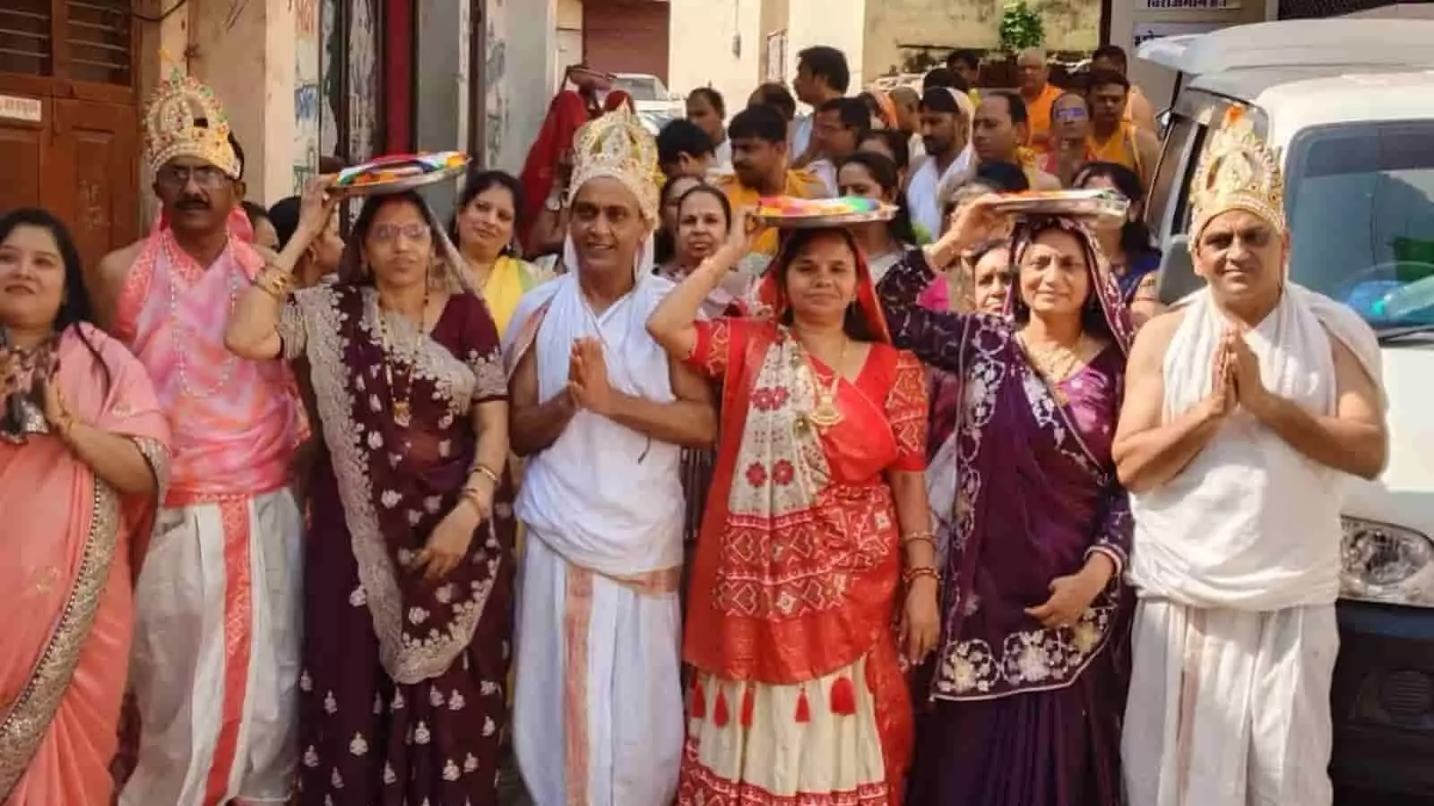 तस्वीर में पारंपरिक वेशभूषा में सजे मुकुटधारी पुरुष और महिलाएं जुलूस के दौरान हाथों में पूजा की थाली थामे हुए दिखाई दे रहे हैं। तस्वीर में पारंपरिक वेशभूषा में सजे मुकुटधारी पुरुष और महिलाएं जुलूस के दौरान हाथों में पूजा की थाली थामे हुए दिखाई दे रहे हैं।