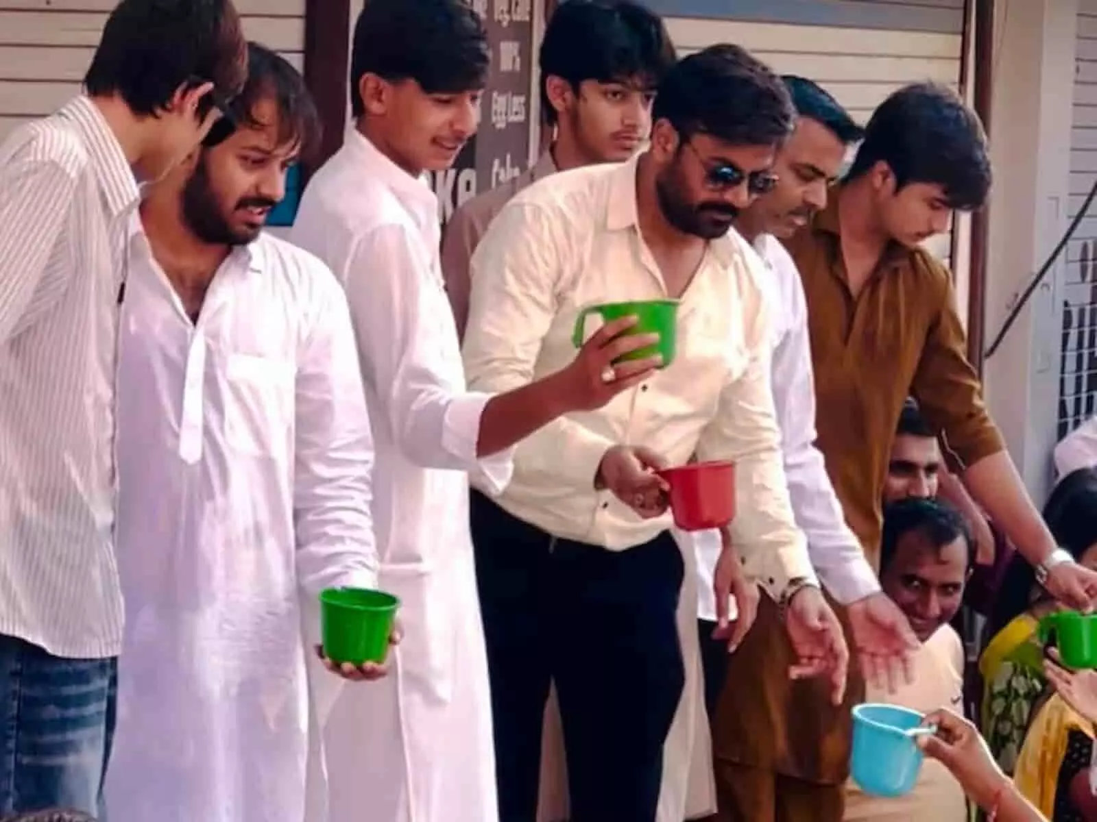 तस्वीर में टेंट के नीचे खड़े सफेद कपड़ों में युवक और अन्य लोग हाथों में पानी के गिलास थामे हुए दिखाई दे रहे हैं। तस्वीर में टेंट के नीचे खड़े सफेद कपड़ों में युवक और अन्य लोग हाथों में पानी के गिलास थामे हुए दिखाई दे रहे हैं।