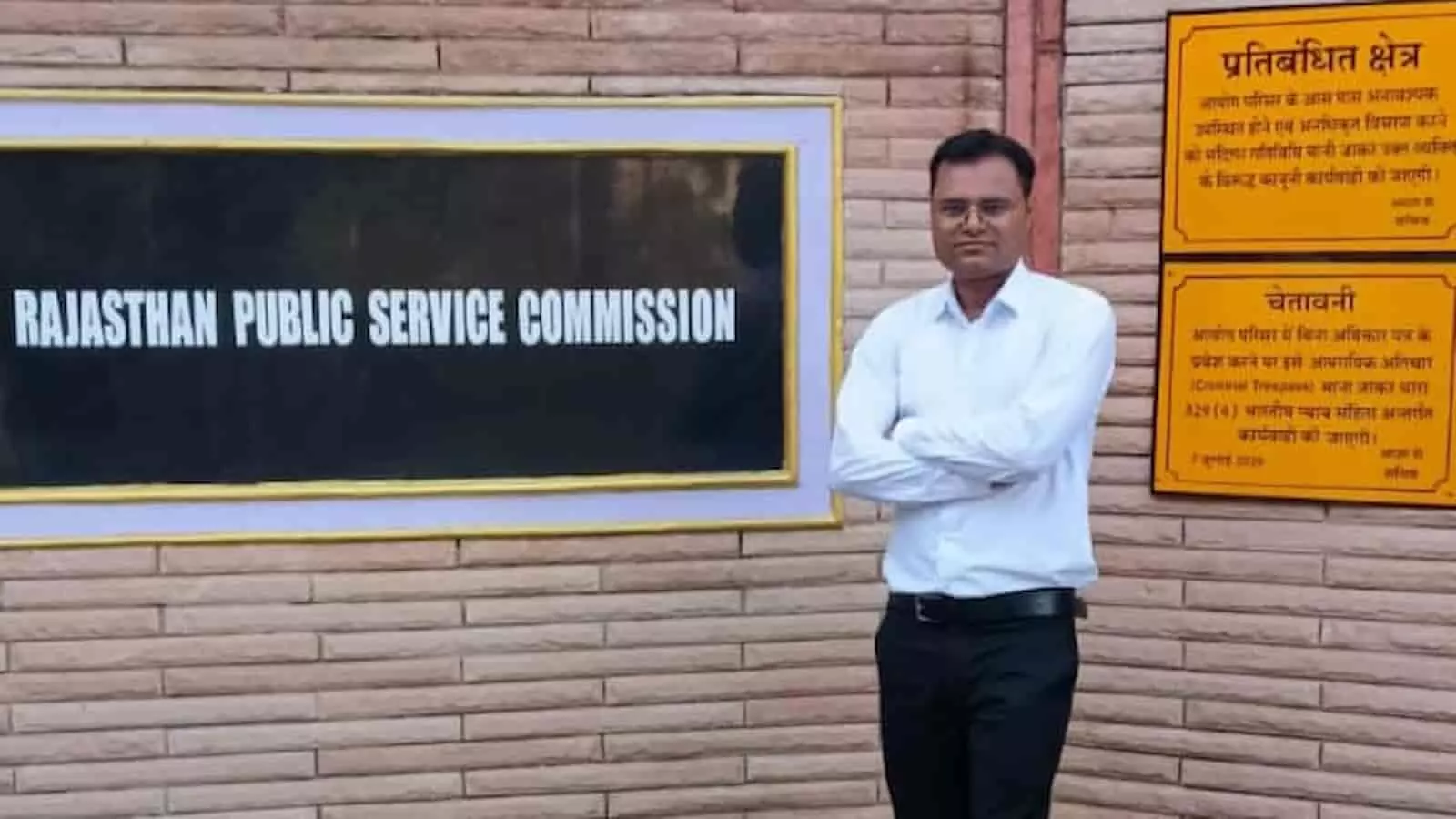 आरपीएससी परिसर के चेतावनी बोर्ड के पास खड़े नवचयनित प्रमोद कुमार शर्मा की तस्वीर। आरपीएससी परिसर के चेतावनी बोर्ड के पास खड़े नवचयनित प्रमोद कुमार शर्मा की तस्वीर।