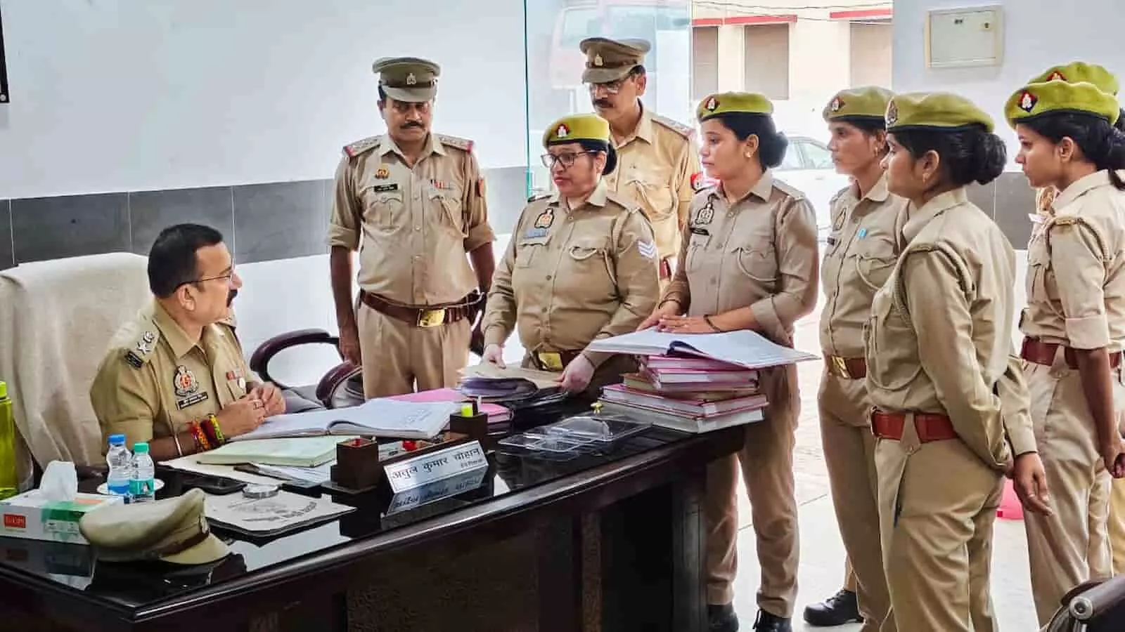 तस्वीर में एक कमरे में टेबल के पास बैठे अधिकारी और उनके सामने खड़ी महिला पुलिसकर्मियों का दल दिखाई दे रहा है। तस्वीर में एक कमरे में टेबल के पास बैठे अधिकारी और उनके सामने खड़ी महिला पुलिसकर्मियों का दल दिखाई दे रहा है।