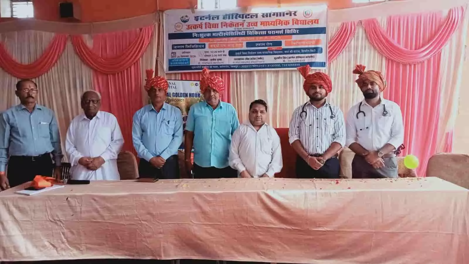 हिंडौन सिटी के चिकित्सा शिविर में बैनर के सामने मंच पर खड़े आयोजक और चिकित्सक। हिंडौन सिटी के चिकित्सा शिविर में बैनर के सामने मंच पर खड़े आयोजक और चिकित्सक।
